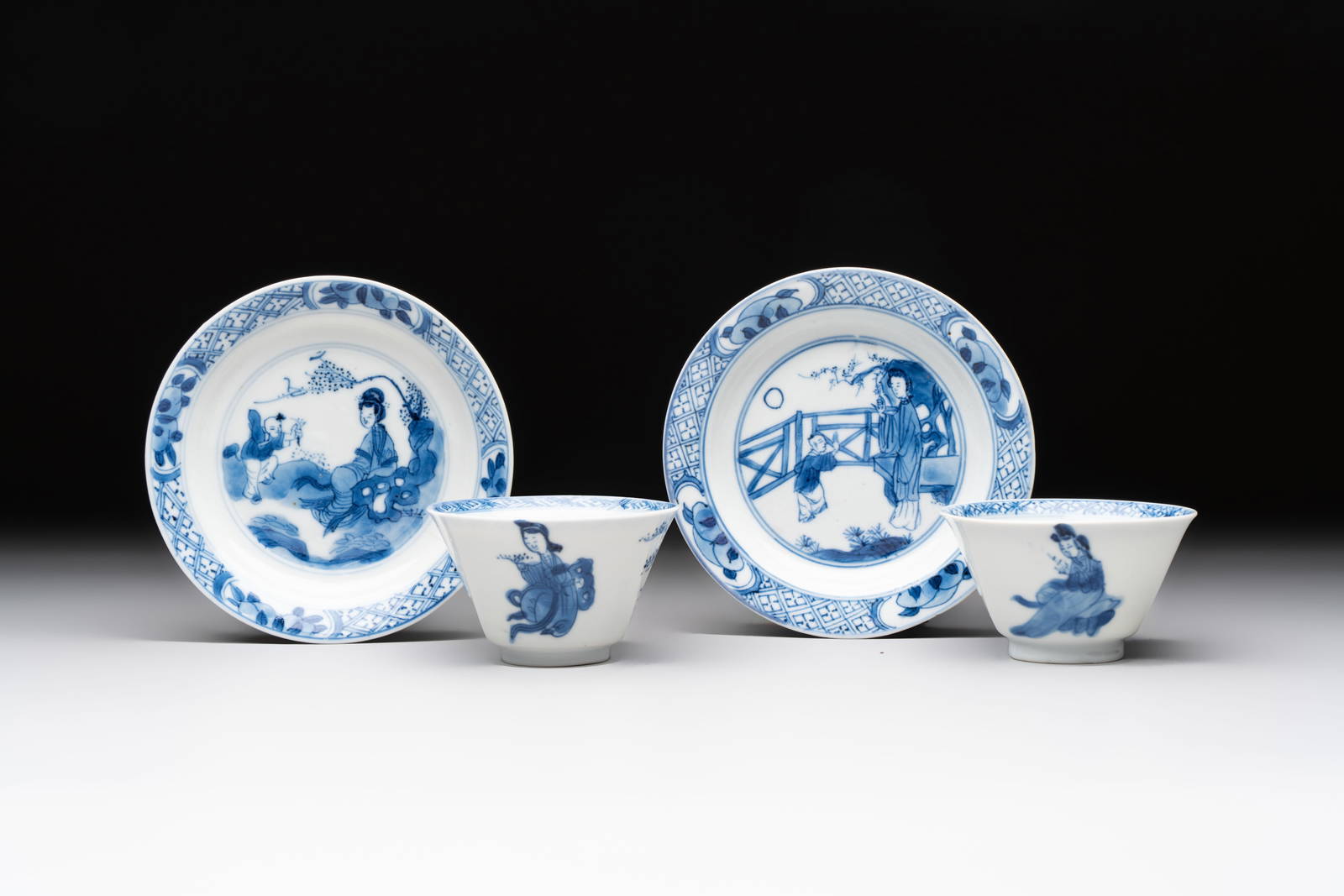 A pair of Chinese blue and white 'elegant beauty and boy' cups and saucers, Chenghua mark, Kangxi