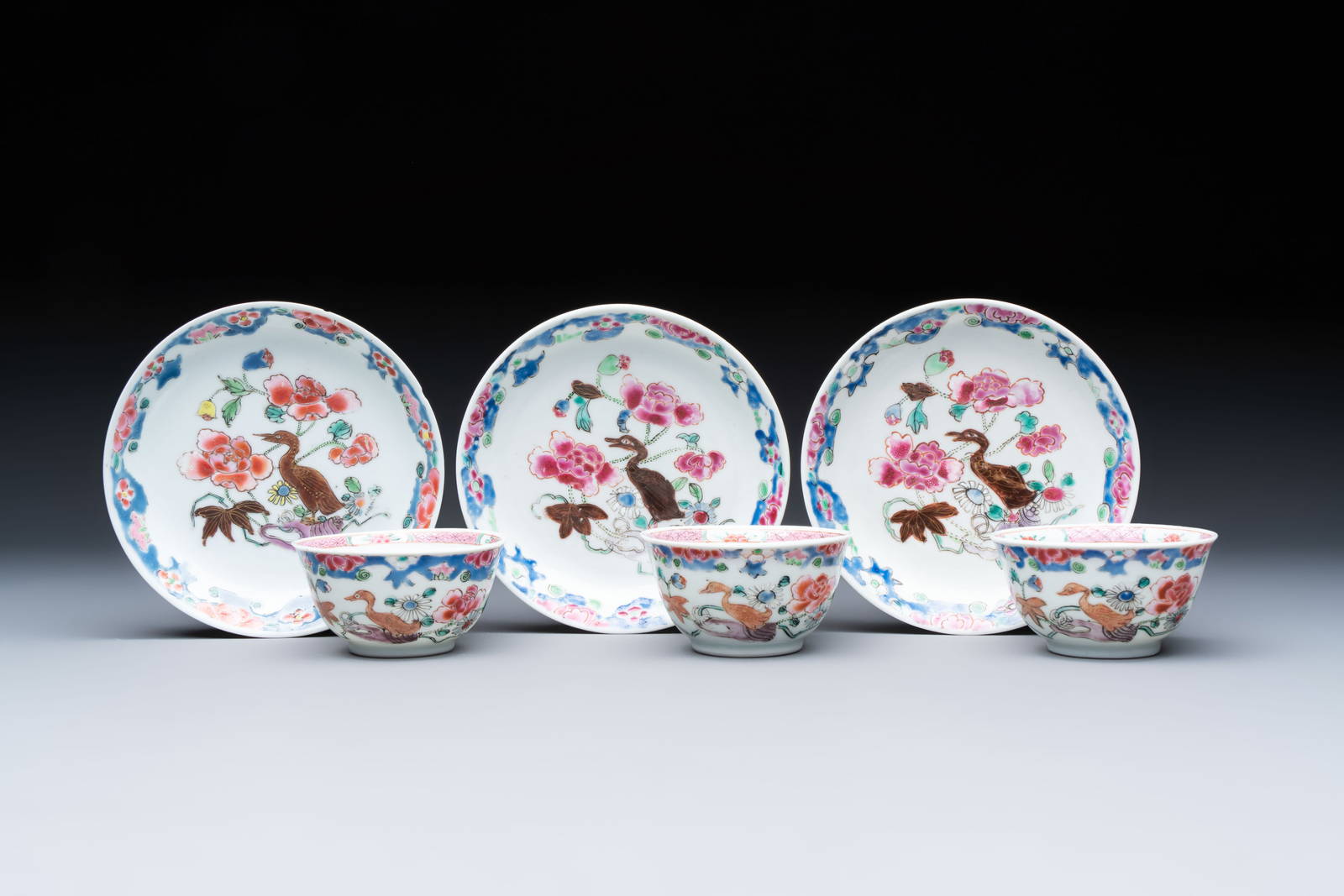 Three Chinese famille rose cups and saucers with a duck among flowering branches, Yongzheng/Qianlong