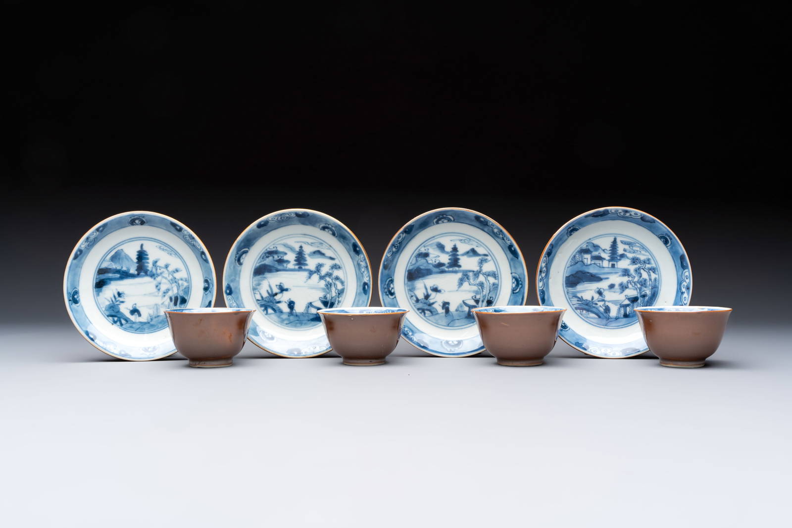 Four Chinese blue and white capucin-ground cups and saucers with landscape design, Yongzheng