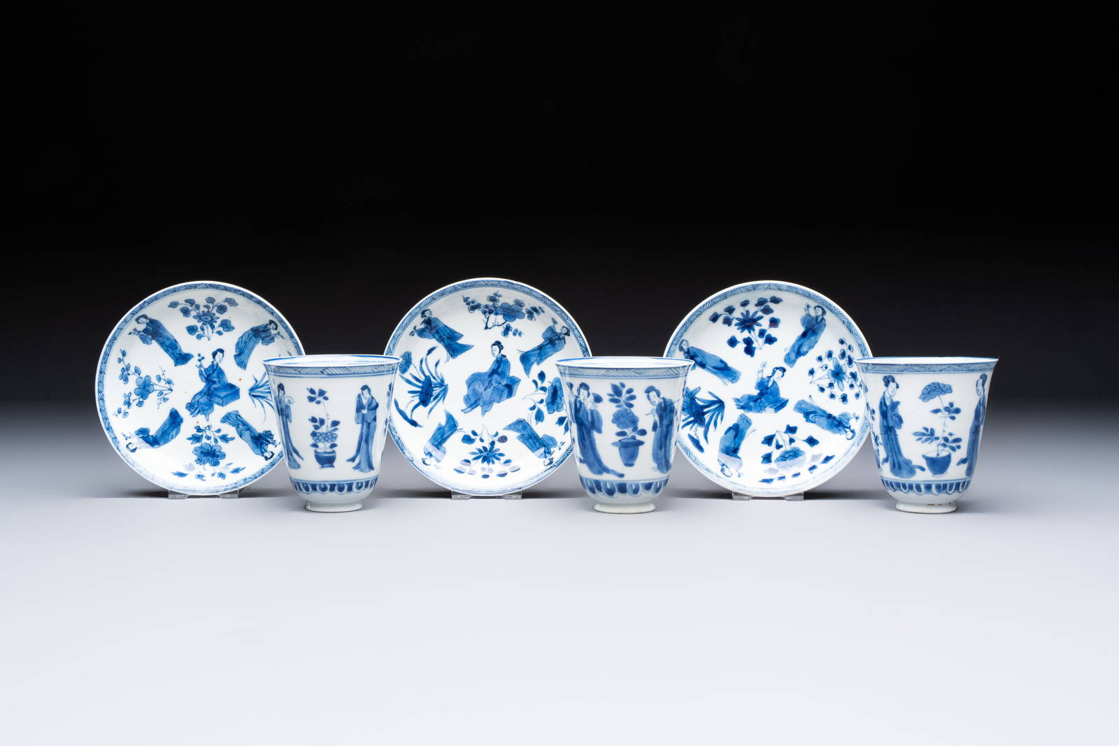 Three Chinese blue and white 'Elegant Beauties' cups and saucers, Chenghua and jade marks, Kangxi