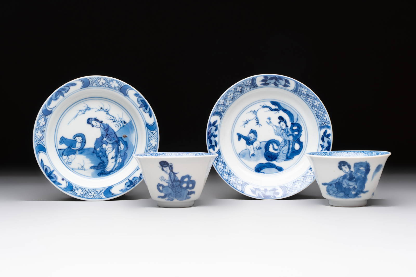 A pair of Chinese blue and white 'Elegant Beauty and Boy' cups and saucers, Chenghua mark, Kangxi