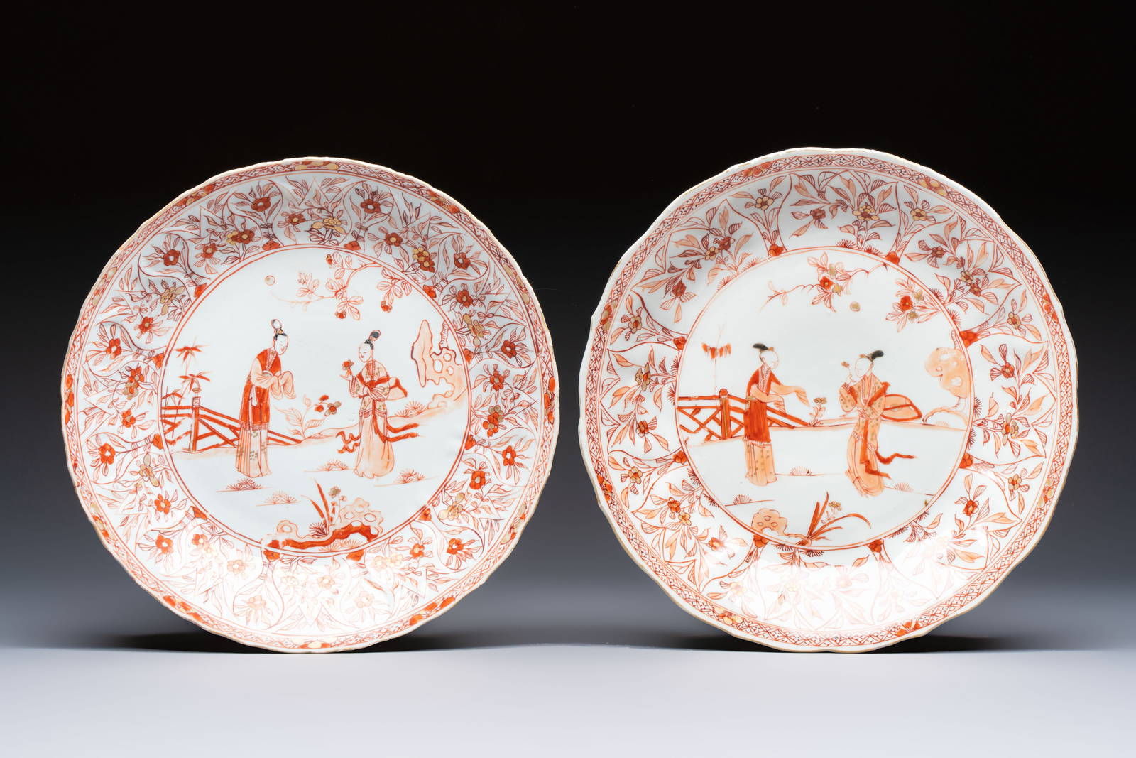 A pair of Chinese iron-red and gilt-decorated 'Elegant Beauties in a Garden' dishes, Kangxi