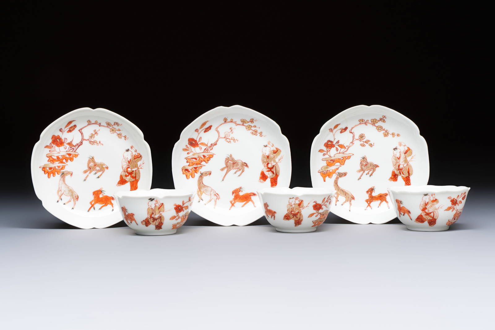 Three fine Chinese eggshell iron-red and gilt-decorated 'Boy and Goats' cups and saucers, Yongzheng