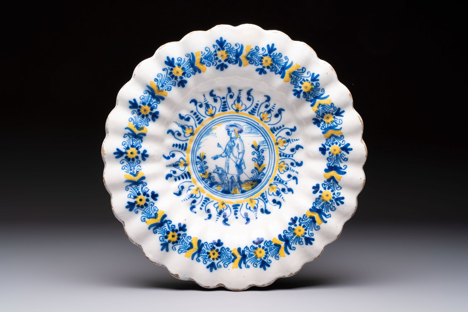 A polychrome lobed Dutch Delft 'Compendario' dish with a shepherd with his dog, 17th C.: A polychrome lobed Dutch Delft 'Compendario' dish with a shepherd with his dog, 17th C. Dia.: 33,5 cm
