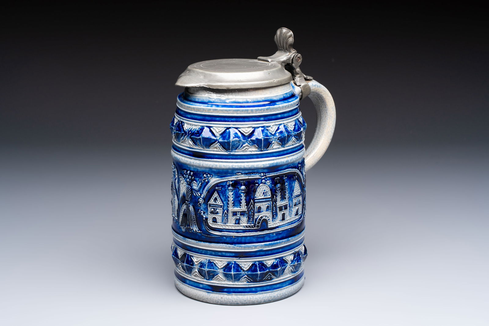 A Westerwald stoneware tankard with a mounted pewter lid, Germany, 18th C.: A Westerwald stoneware tankard with a mounted pewter lid, Germany, 18th C. L.: 14 cm - H.: 20,8 cm (incl. pewter mount) Provenance: - An important private collection from Antwerp, Belgium.