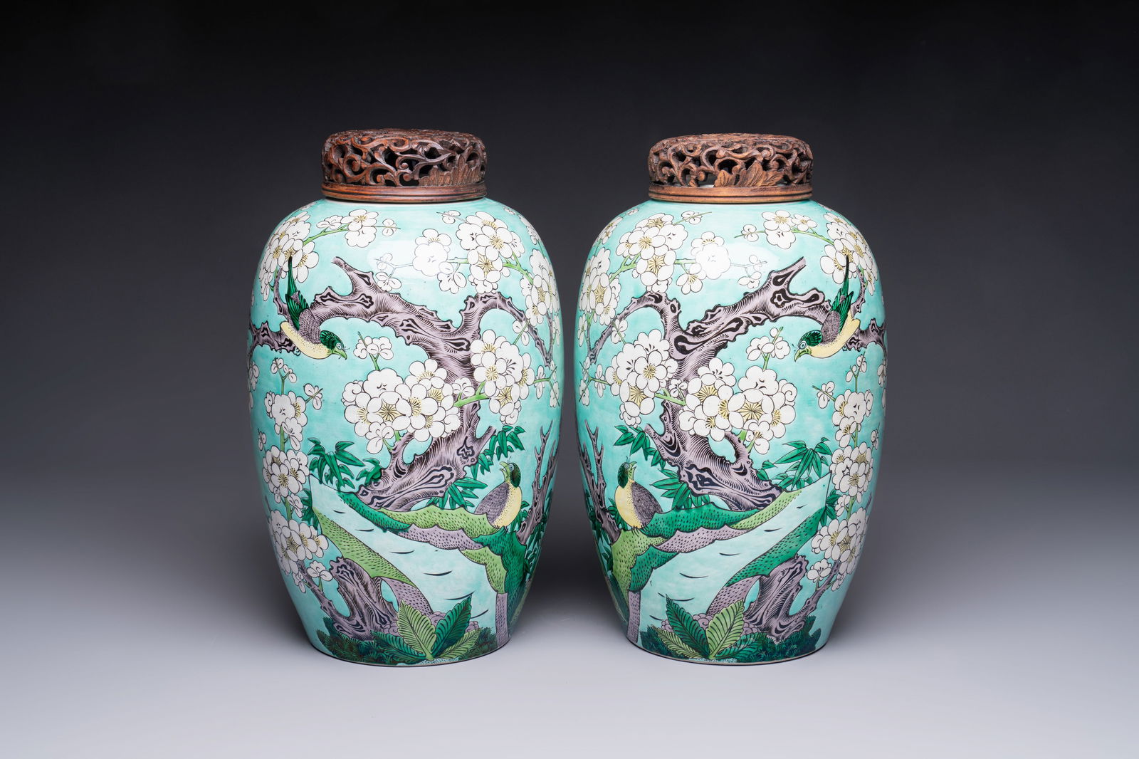 A pair of fine Chinese famille verte turquoise-ground 'Magpie and Prunus' jars with reticulated: A pair of fine Chinese famille verte turquoise-ground 'Magpie and Prunus' jars with reticulated wooden covers, 19th C. H.: 37,5 cm (incl. cover)