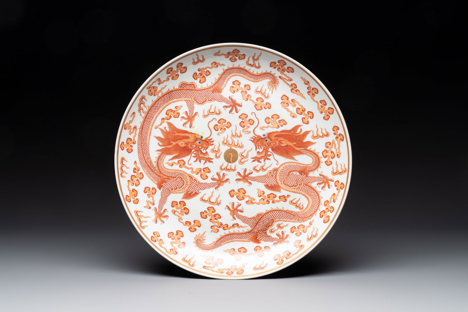 A Chinese gilt iron-red 'dragons and clouds' dish, Guangxu mark, 20th C.: A Chinese gilt iron-red 'dragons and clouds' dish, Guangxu mark, 20th C. Dia.: 34,4 cm