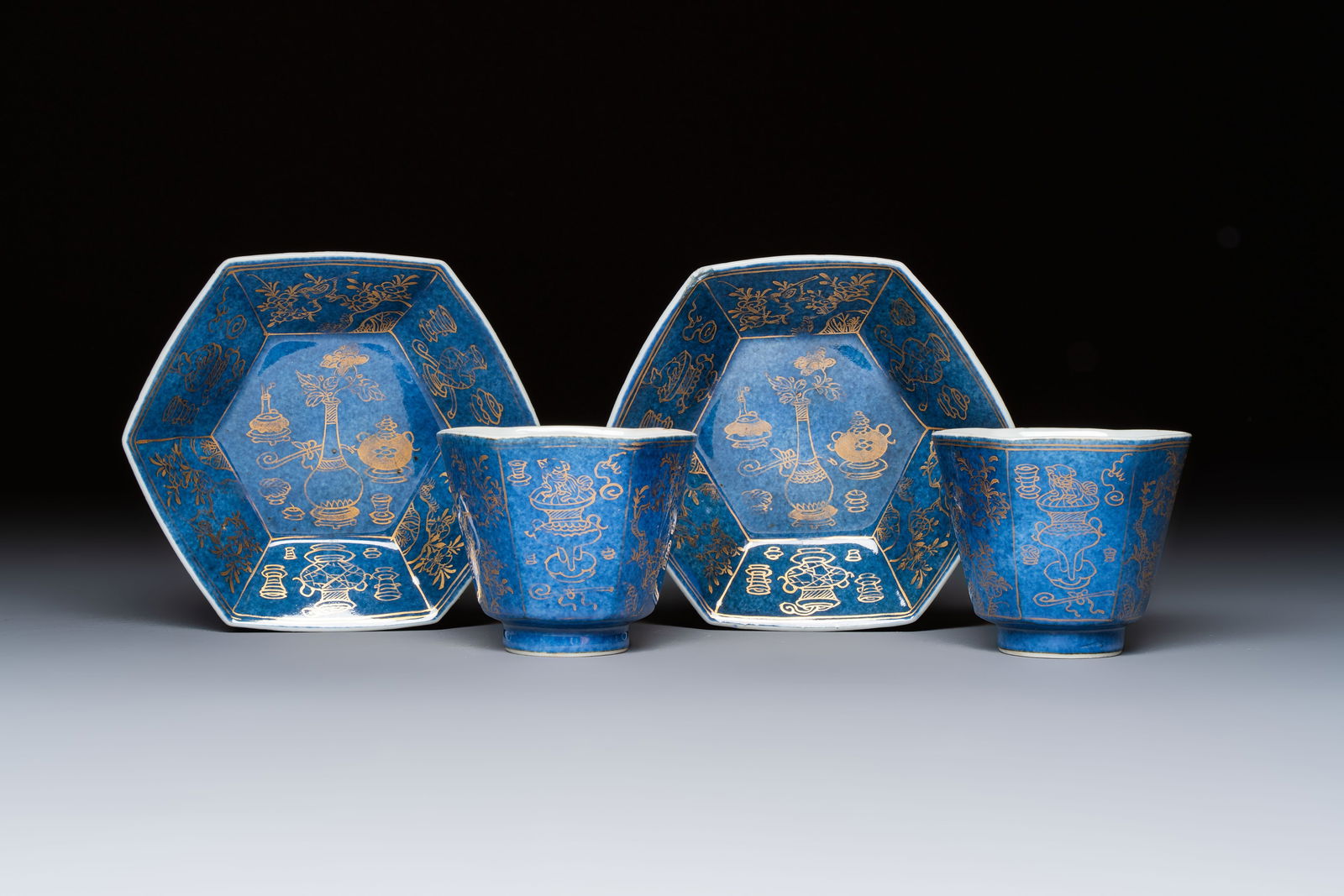 A pair of Chinese gilt-decorated powder-blue-ground 'Antiquities' cups and saucers, lingzhi mark, (1 of 9)