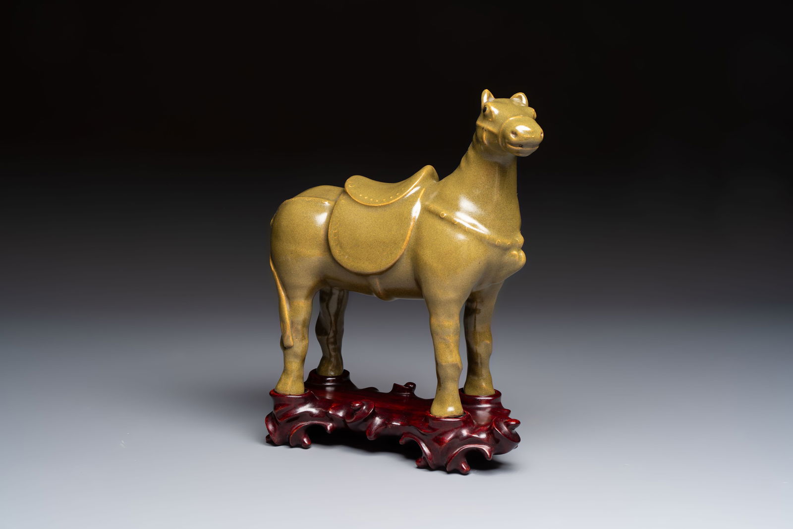 A Chinese teadust-glazed model of a horse on a wooden stand, Republic: A Chinese teadust-glazed model of a horse on a wooden stand, Republic L.: 24,5 cm - H.: 28,5 cm (incl. stand) L.: 24,5 cm - H.: 24 cm (excl. stand)