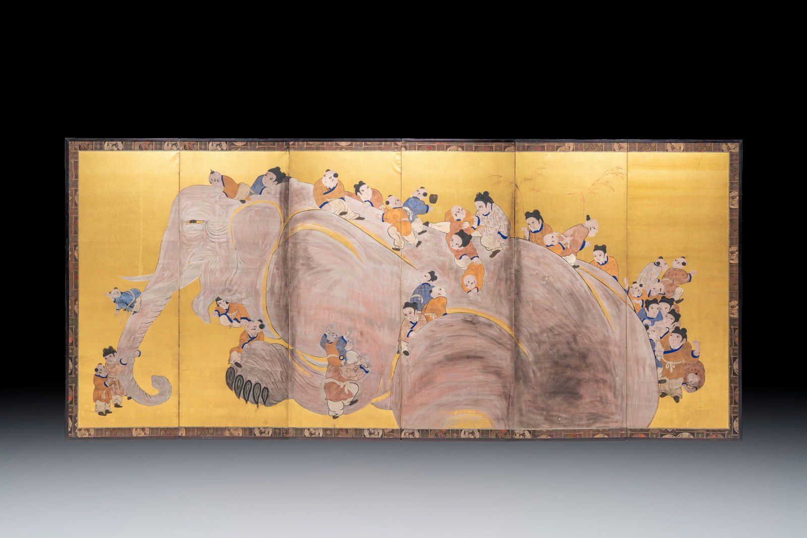 A Japanese six-panel folding screen or by?bu depicting children playing with an elephant, ink, (1 of 2)