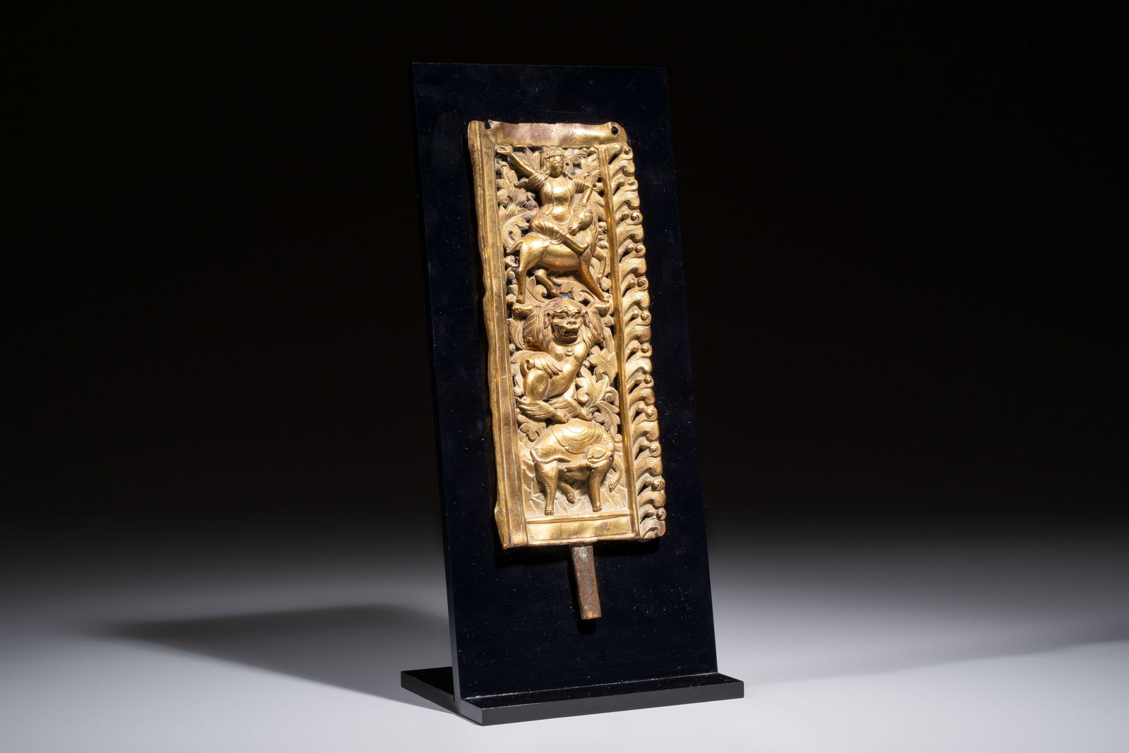 A fine Tibetan gilt-copper repoussé plaque depicting a Dharmapala, a lion and an elephant, on a (1 of 5)