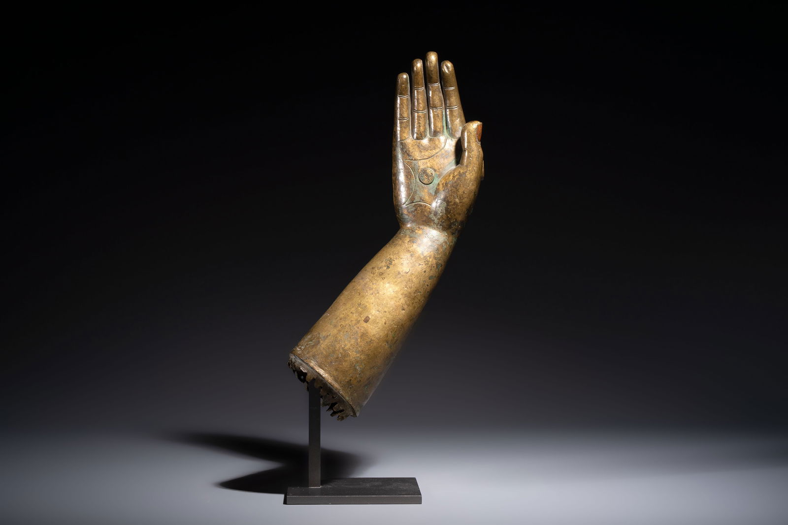 A rare and large Tibetan bronze forearm of a Buddhist figure with a chakra design, on a later metal (1 of 8)