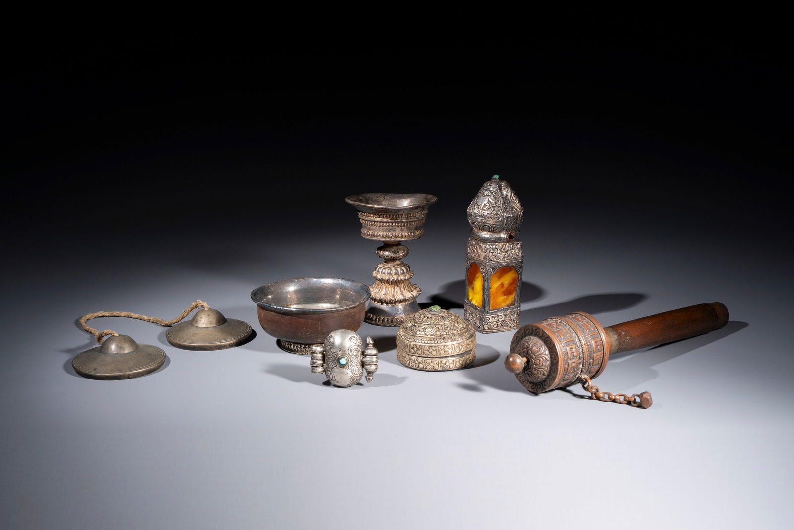 A varied collection of seven Tibetan ritual utensils, including a turquoise-inlaid silver relic: A varied collection of seven Tibetan ritual utensils, including a turquoise-inlaid silver relic holder, 19/20th C. L.: 27,5 cm (the prayer wheel) H.: 14 cm (the seal) Dia.: 10,4 cm- H.: 4,7 cm (the bo