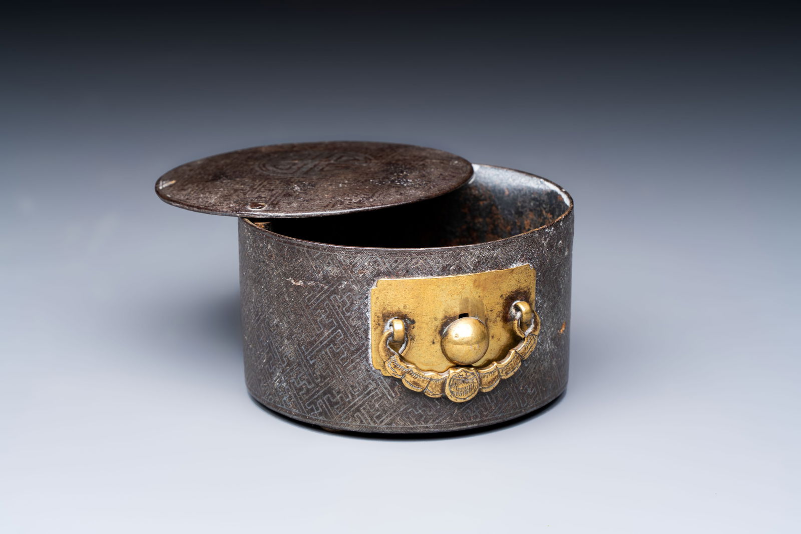 A Korean silver-inlaid iron tripod box with a gilt-bronze bat-shaped handle, Joseon, 18th C.: A Korean silver-inlaid iron tripod box with a gilt-bronze bat-shaped handle, Joseon, 18th C. Dia.: 9,1 cm - H.: 5,7 cm Weight: 425 grams