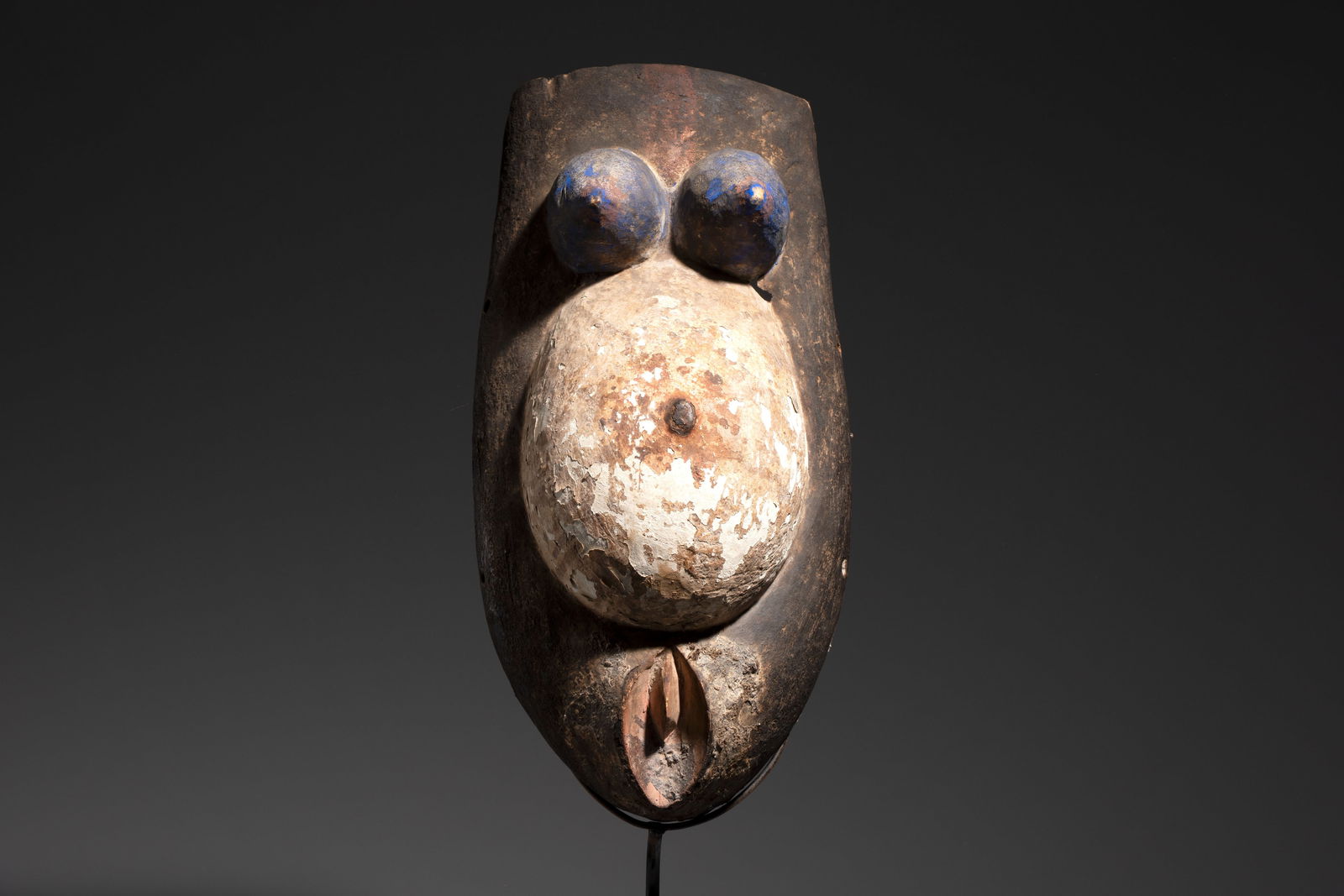 A polychromed wooden fertility belly mask from the Yoruba people, West Africa, 20th C.: A polychromed wooden fertility belly mask from the Yoruba people, West Africa, 20th C. Dim.: 22,5 x 45 x 14 cm (excl. stand)