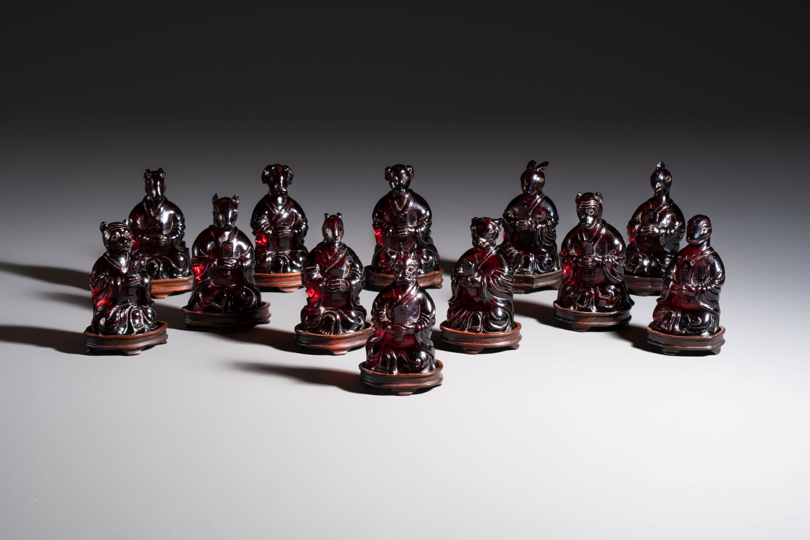 A rare complete set of 12 Chinese cherry amber 'Zodiac' figures on wooden stands, Qianlong mark, (1 of 19)