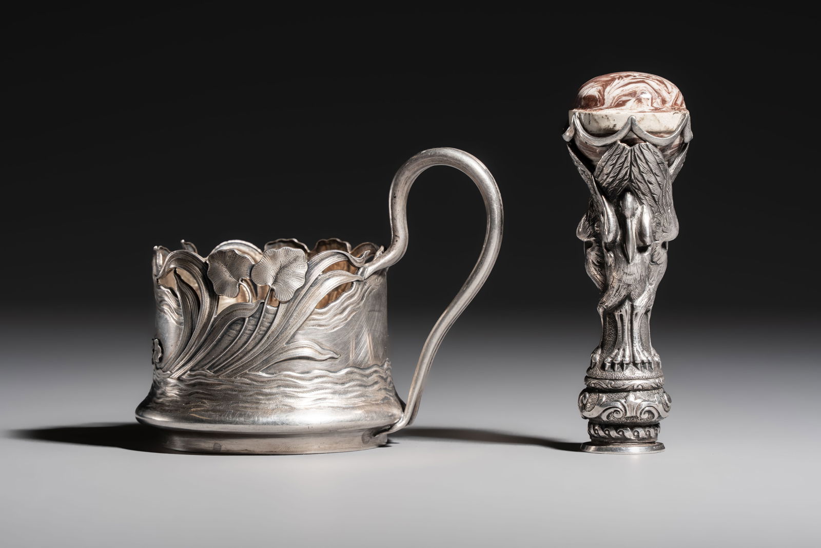 A Russian parcel-gilt silver tea-glass holder or 'podstakannik' and a silver monogram 'herons' seal: A Russian parcel-gilt silver tea-glass holder or 'podstakannik' and a silver monogram 'herons' seal stamp, 19/20th C. H.: 11 cm (the seal) L.: 11 cm - H.: 9 cm (the podstakannik) Weight: - 330 grams (