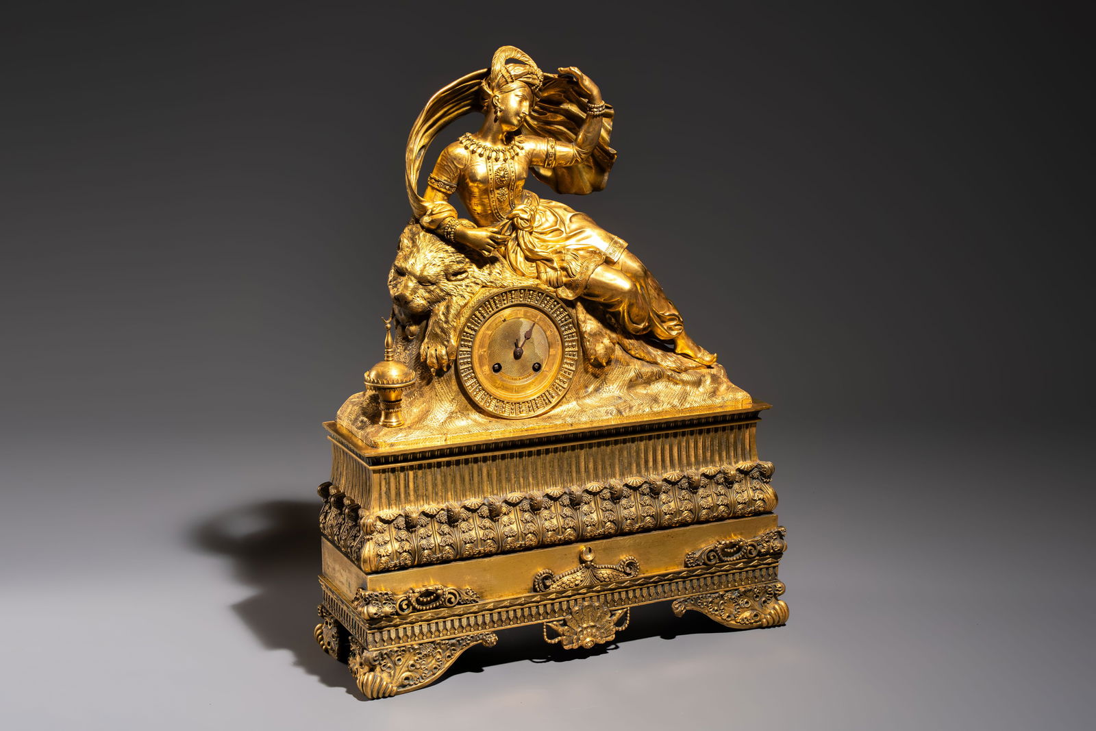 A gilt-bronze 'Oriental Beauty Reclining on a Lion Skin' mantel clock, France, first quarter 19th C.: A gilt-bronze 'Oriental Beauty Reclining on a Lion Skin' mantel clock, France, first quarter 19th C. Dim.: 40,5 x 14 x 52 cm Weight: 10,9 kilograms