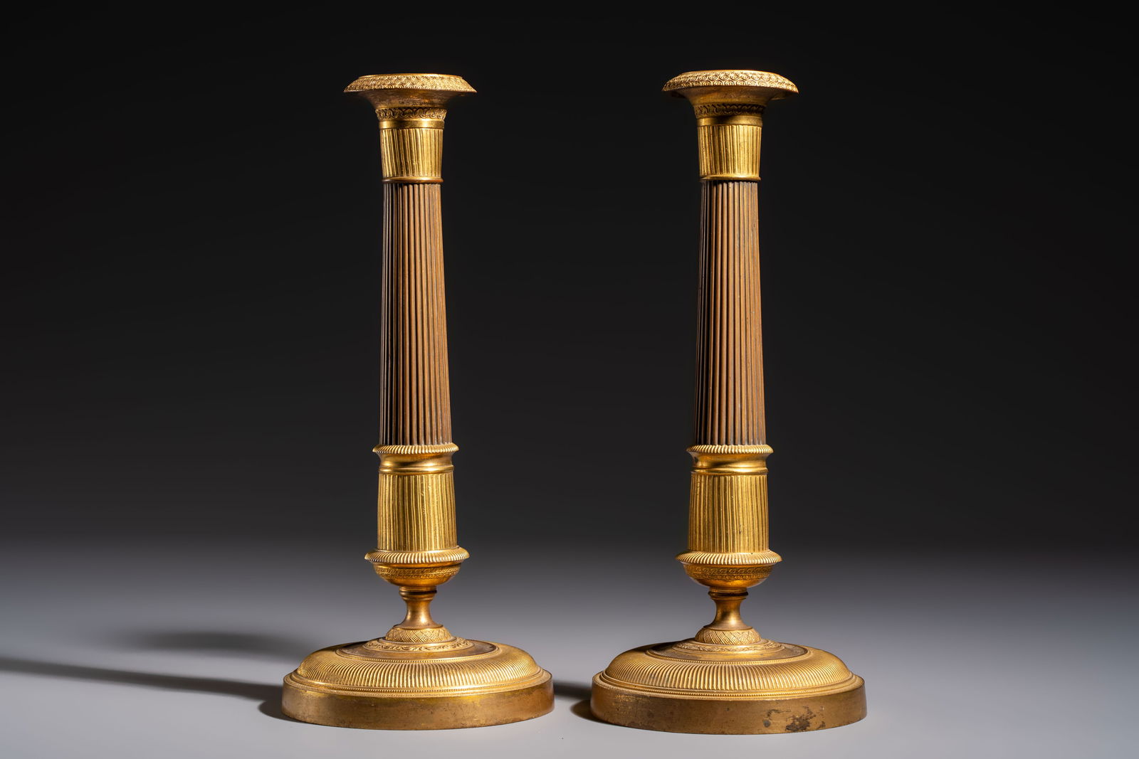 A pair of Empire parcel-gilt bronze candlesticks, early 19th C. (1 of 6)
