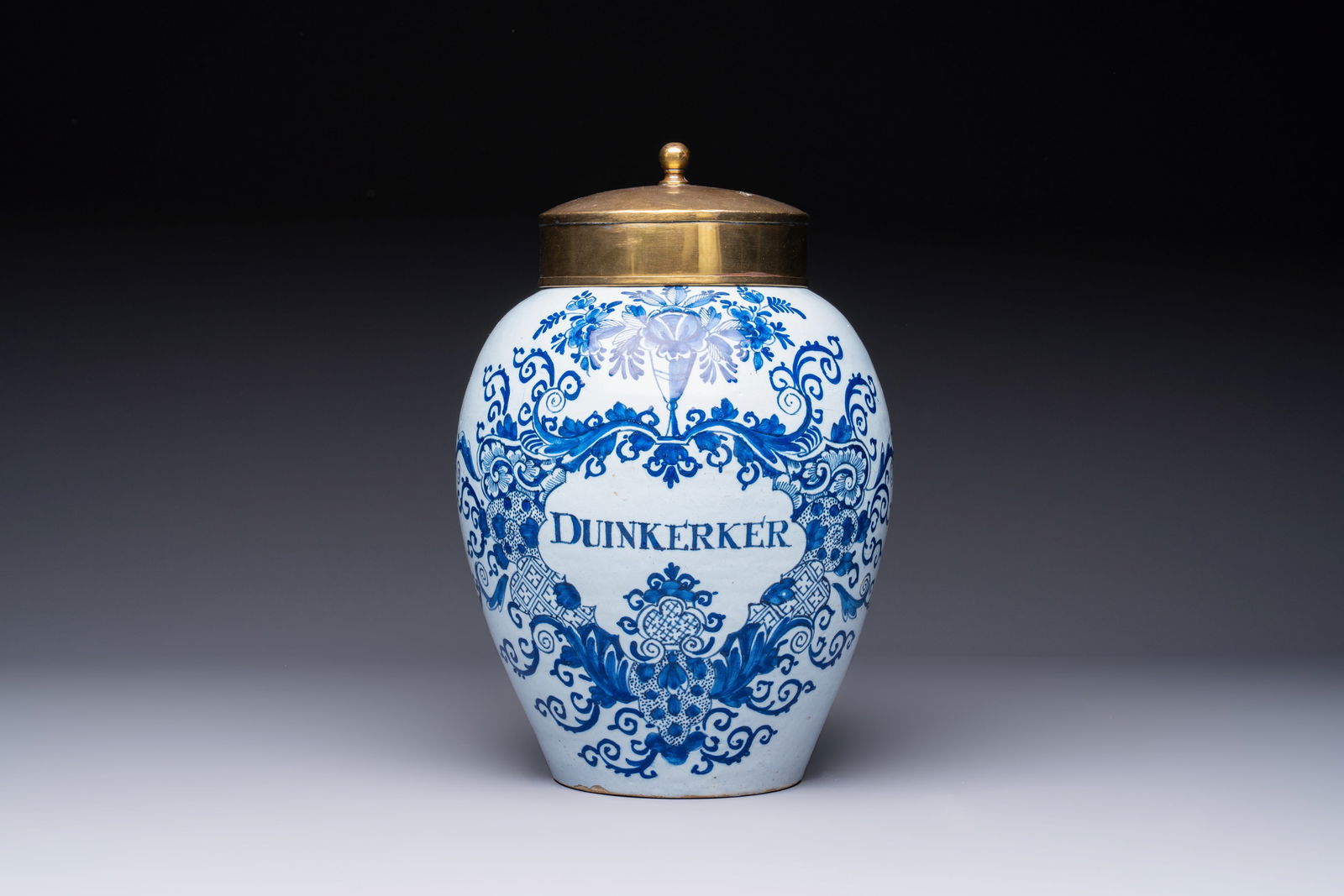 A blue and white Dutch Delft tobacco jar inscribed 'Duinkerker' with brass lid, 18th C. (1 of 7)