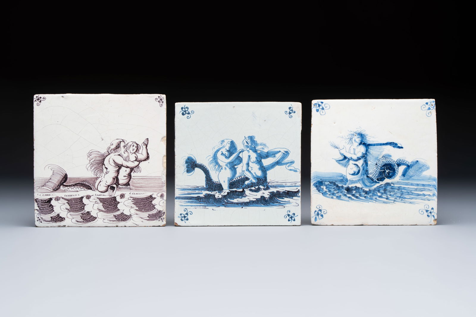 Two blue and white and one manganese Dutch Delft tiles with sea creatures, 17th C.: Two blue and white and one manganese Dutch Delft tiles with sea creatures, 17th C. Dim.: ca. 13,2 x 13,3 x 1 cm (the largest) Dim.: ca. 12,6 x 12,4 x 1 cm (the smallest)