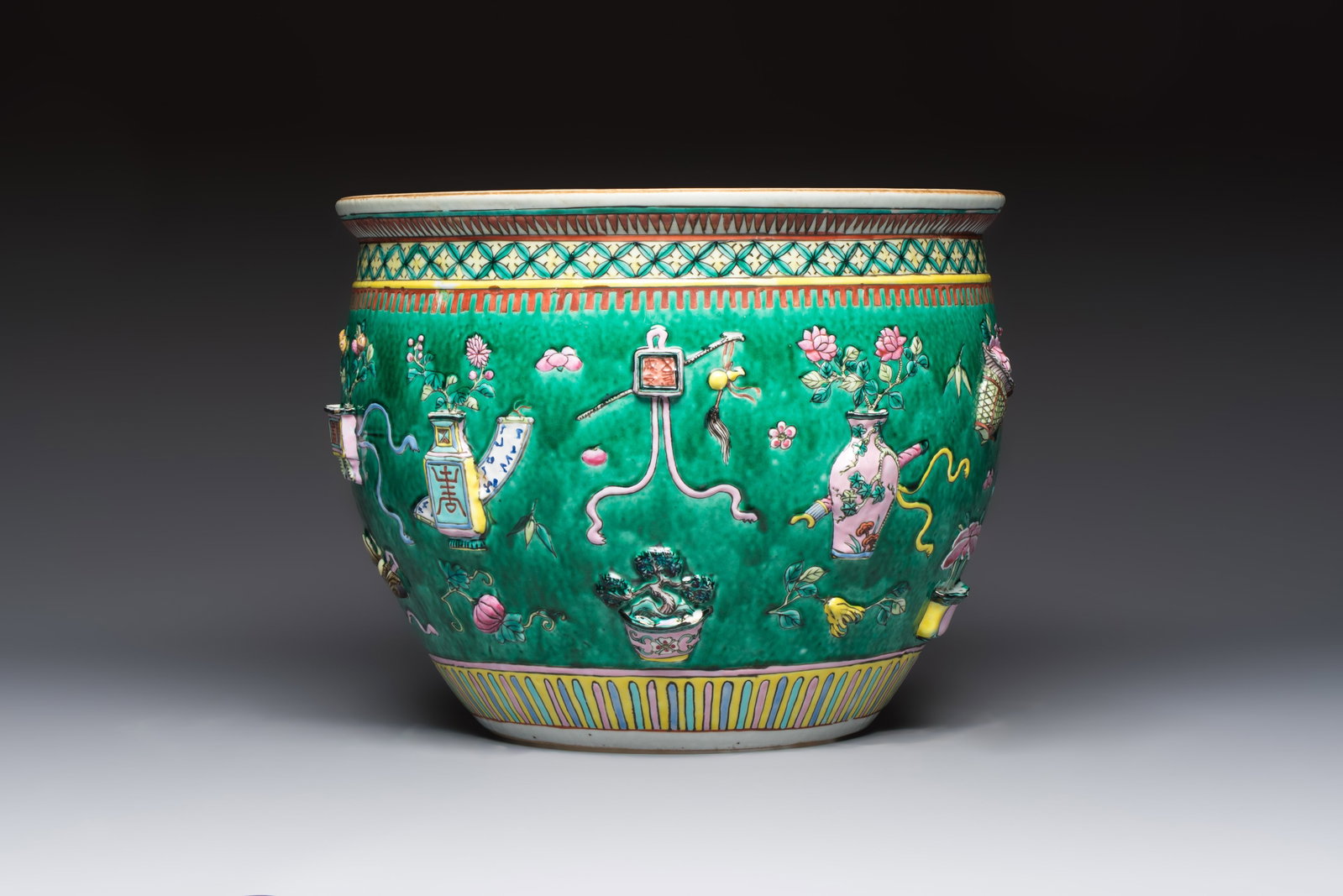 A Chinese famille rose green-ground 'Antiquities' fish bowl or jardinière with applied relief: A Chinese famille rose green-ground 'Antiquities' fish bowl or jardinière with applied relief design, 19th C. Dia.: 31,8 cm - H.: 25 cm