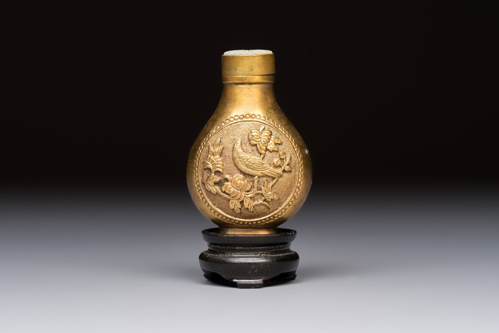 A Chinese gilt-bronze and mother-of-pearl-inlaid snuff bottle with birds among flowering branches,: A Chinese gilt-bronze and mother-of-pearl-inlaid snuff bottle with birds among flowering branches, Guangxu mark and of the period H.: 8 cm (incl. stopper and stand) H.: 6,5 cm (incl. stopper, excl. st