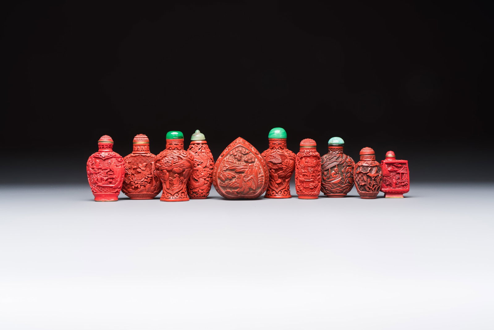 Nine Chinese cinnabar lacquer snuff bottles and a covered box, Qianlong marks, 19/20th C.: Nine Chinese cinnabar lacquer snuff bottles and a covered box, Qianlong marks, 19/20th C. H.: 9 cm (the tallest, incl. stopper) H.: 5,9 cm (the smallest, incl. stopper) Dim.: 6,7 x 7,3 x 5,2 cm (the c