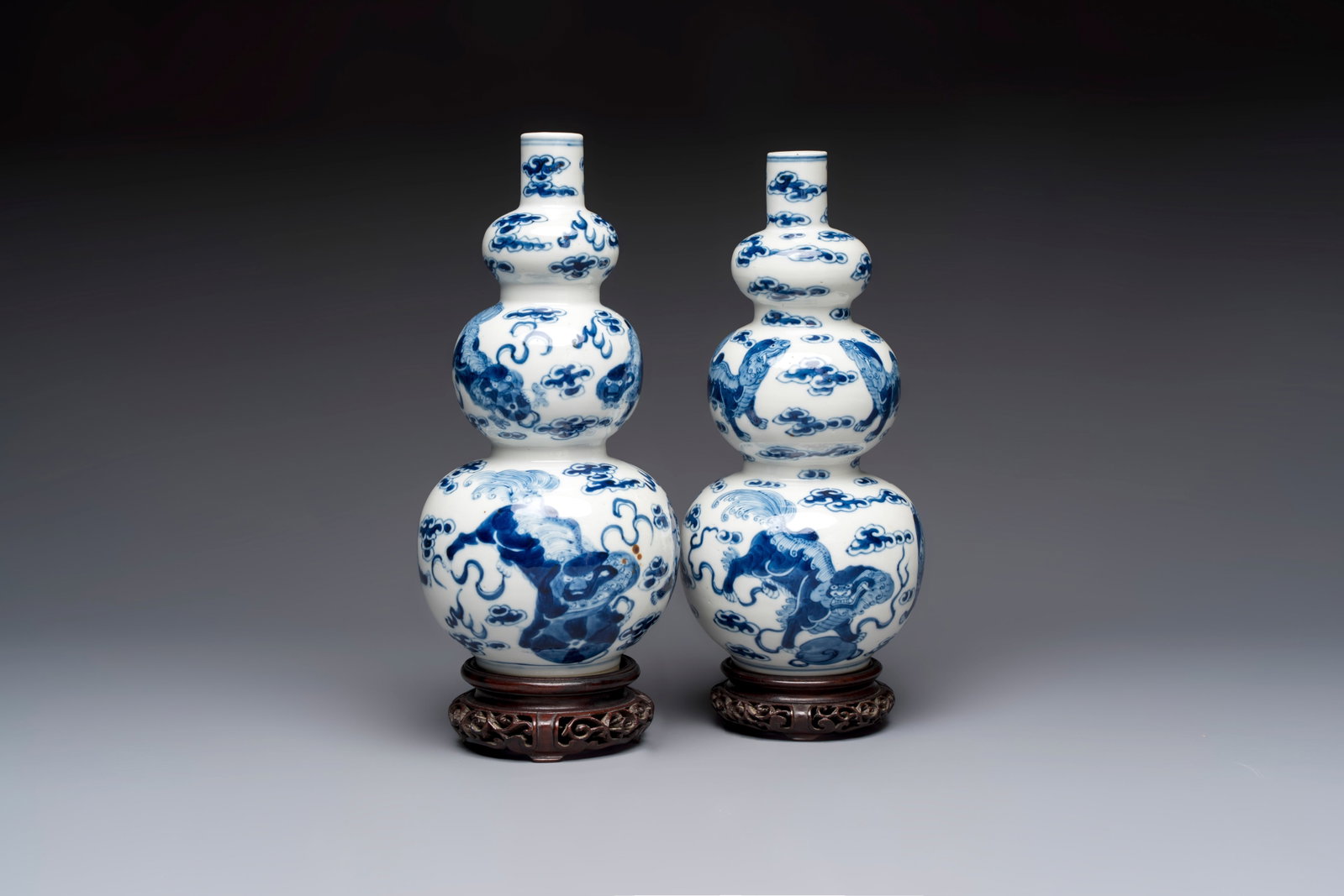 A pair of Chinese blue and white 'Buddhist Lions' triple gourd vases on reticulated wooden stands, (1 of 9)