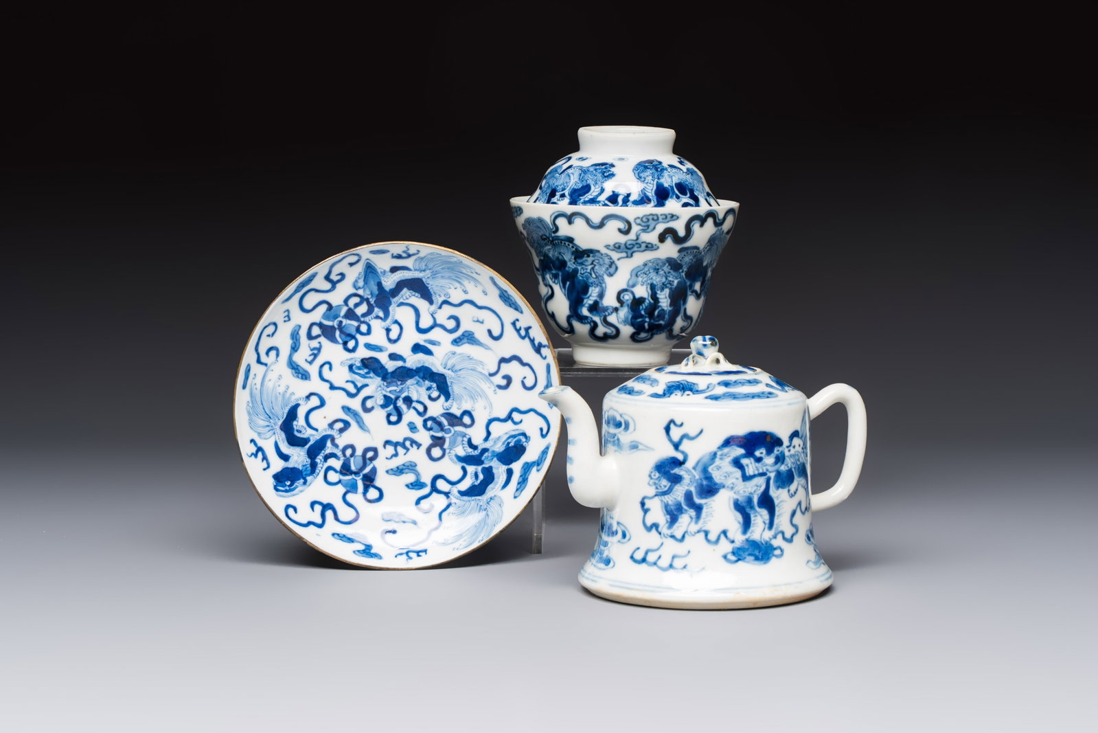 A Chinese blue and white 'Buddhist Lion' teapot, covered bowl and a saucer, various marks, 19th C.: A Chinese blue and white 'Buddhist Lion' teapot, covered bowl and a saucer, various marks, 19th C. L.: 13,2 cm - H.: 9,8 cm (the teapot, incl. cover) Dia.: 9,3 cm - H.: 9,8 cm (the bowl, incl. cover) 