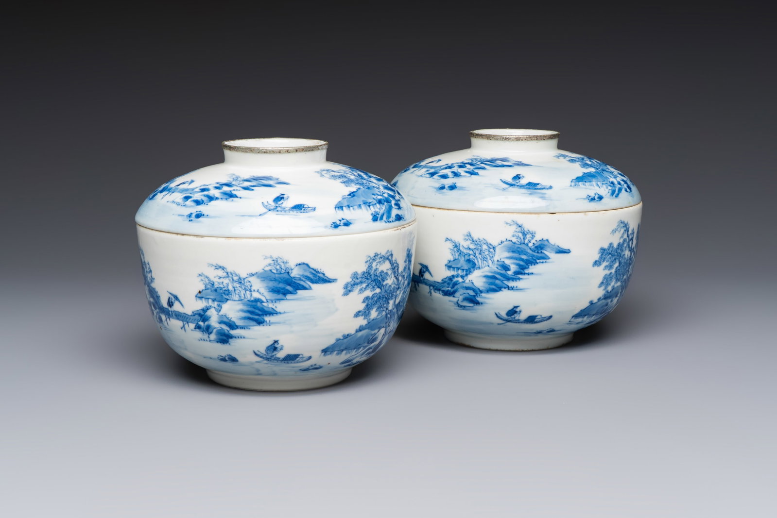 A pair of Chinese blue and white 'Bleu de Hue' covered bowls with landscape design, Phong Vu Quy Chu: A pair of Chinese blue and white 'Bleu de Hue' covered bowls with landscape design, Phong Vu Quy Chu marks, 19th C. Dia.: 15,4 cm - H.: 12,9 cm (incl. cover)