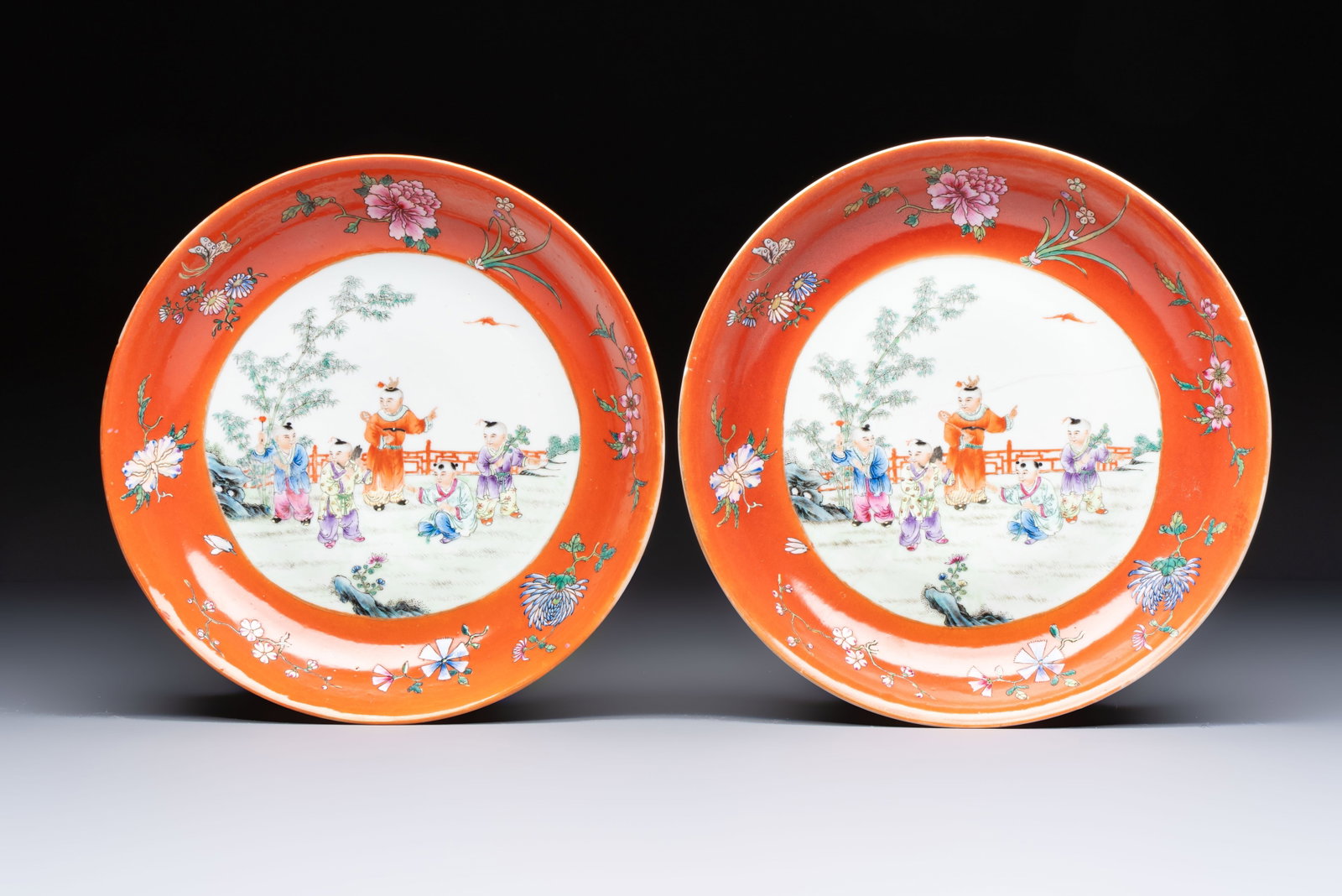 A pair of Chinese famille rose coral-ground 'Playing Boys' plates, Jiaqing marks, Republic (1 of 2)