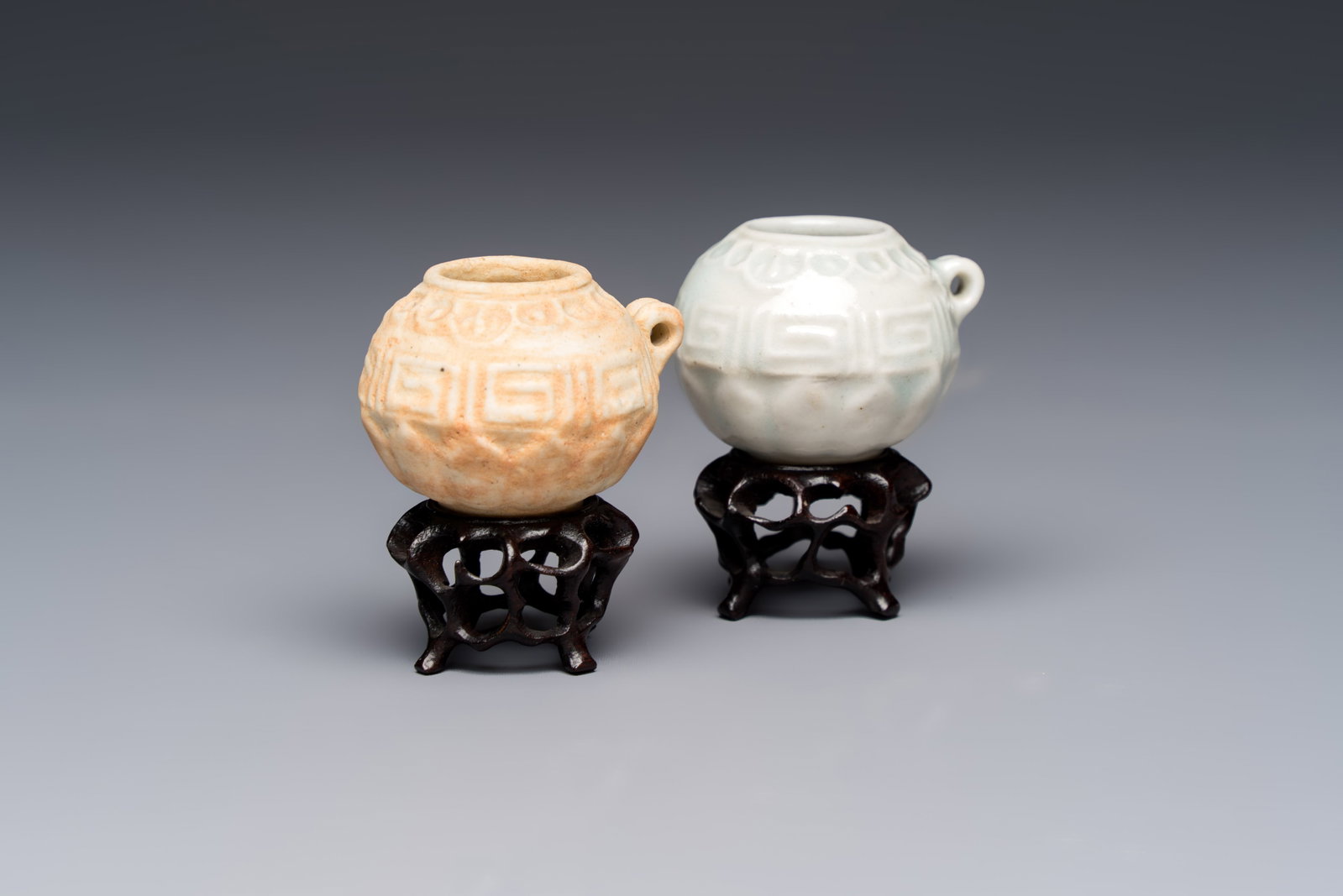 A pair of Chinese bird feeders with moulded design, one unglazed, on later wooden stands, Song: A pair of Chinese bird feeders with moulded design, one unglazed, on later wooden stands, Song H.: 4,7 cm (incl. stand) Provenance: -Collection of Dr Carl Kempe (1884-1967). - A Belgian private collec