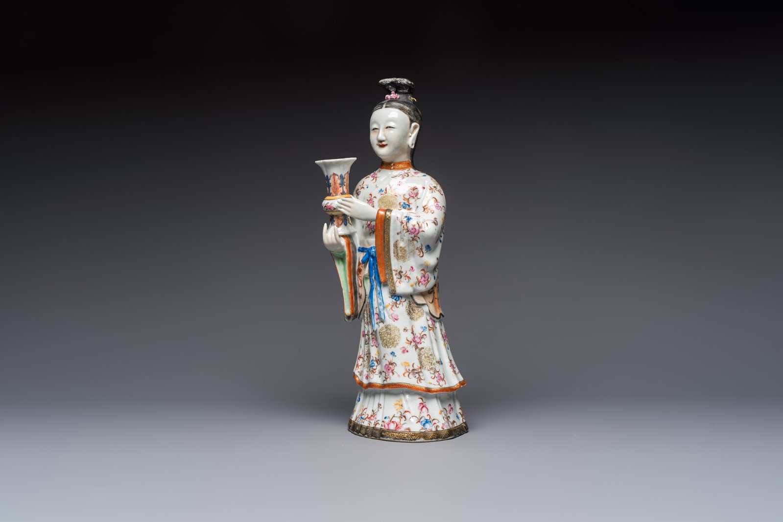 A Chinese famille rose candle holder in the shape of a court lady holding a 'Gu' vase, Qianlong: A Chinese famille rose candle holder in the shape of a court lady holding a 'Gu' vase, Qianlong H.: 41,5 cm Ref.: - Christie's London, 22 April 1991, lot 31 for an identical pair. (sold GBP 18.700,00)