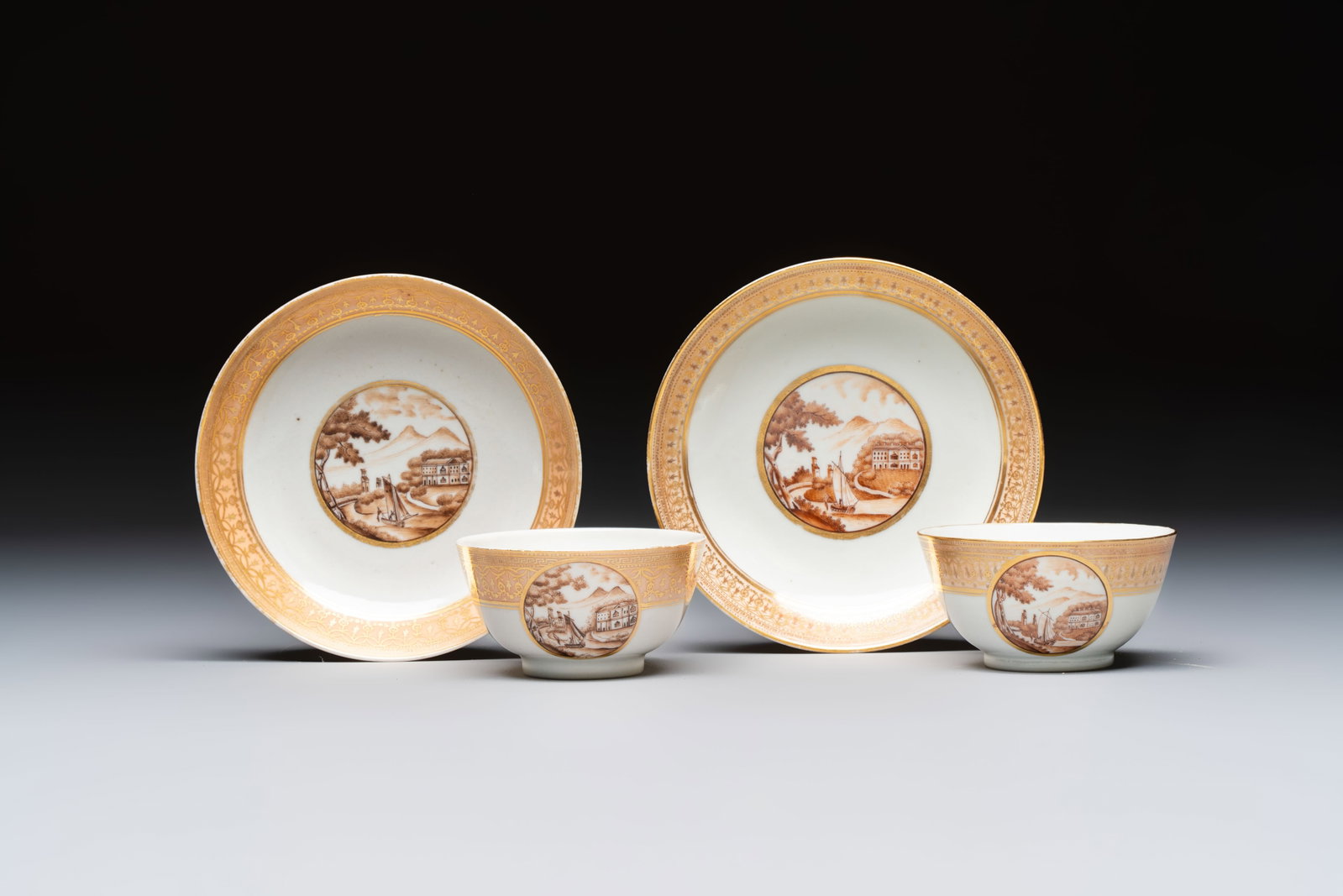 A pair of Chinese gilt-decorated sepia 'Riverscape' cups and saucers, Jiaqing: A pair of Chinese gilt-decorated sepia 'Riverscape' cups and saucers, Jiaqing Dia.: 14,2 cm (the largest saucer) Dia.: 9 cm - H.: 4,6 cm (the largest cup) Dia.: 13,8 cm (the smallest saucer) Dia.: 8,8