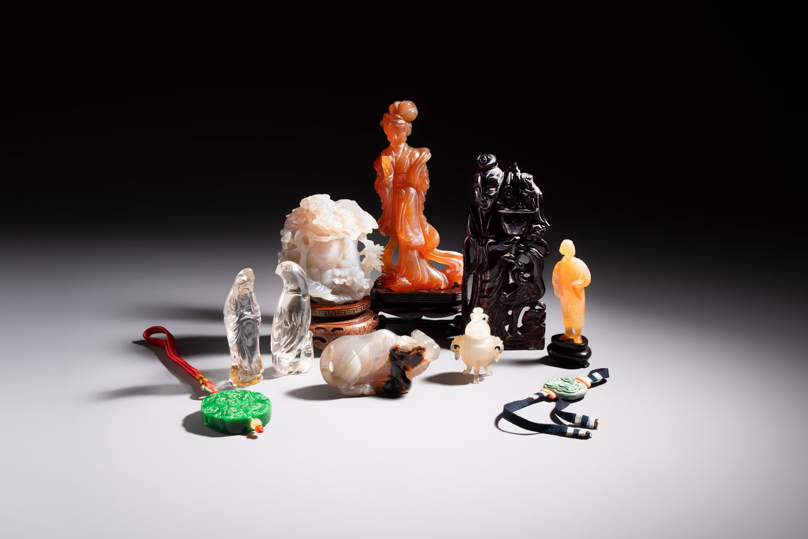 A group of eight Chinese hardstone and cherry amber carvings, 20th C.: A group of eight Chinese hardstone and cherry amber carvings, 20th C. H.: 20,7cm (the tallest, incl. stand) Dim.: ca. 4 x 4 cm (the smallest, excl. ribbon) Weight: 1469 grams (total, excl. stands)