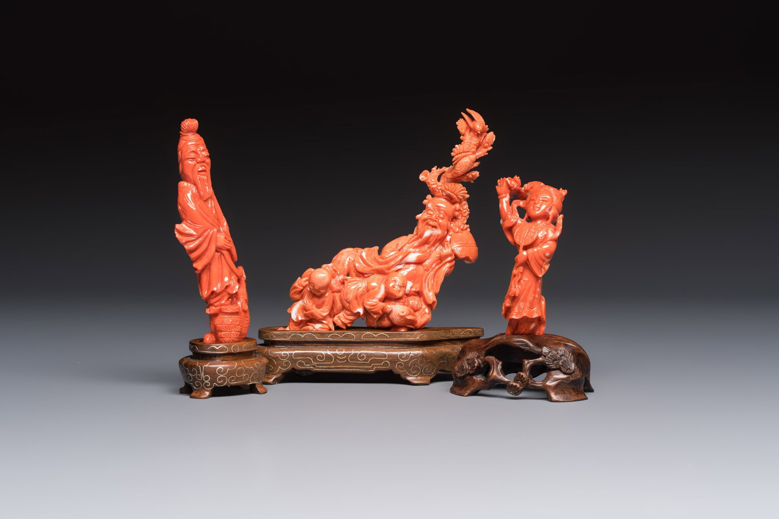Three Chinese red coral carvings on wooden stands, 19/20th C.: Three Chinese red coral carvings on wooden stands, 19/20th C. H.: 13,3 cm (the tallest carving, incl. stand) H.: 11,1 cm (the tallest carving, excl. stand) H.: 9,9 cm (the smallest carving, incl. stan