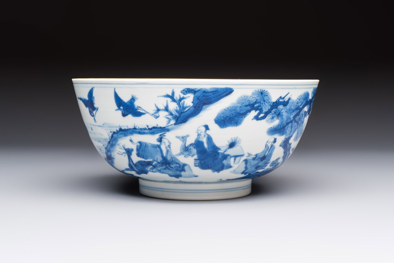 A Chinese blue and white bowl with scholars among cranes and deer, Kangxi mark and of the period: A Chinese blue and white bowl with scholars among cranes and deer, Kangxi mark and of the period Dia.: 19,6 cm - H.: 9,1 cm