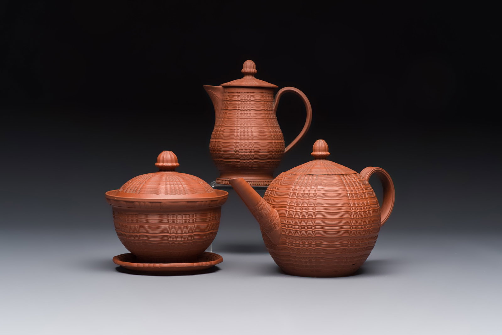 An English 4-piece engine-turned redware tea service, pseudo-Chinese marks, 2nd half 18th C.: An English 4-piece engine-turned redware tea service, pseudo-Chinese marks, 2nd half 18th C. L.: 20,1 cm - H.: 12,9 cm (the teapot, incl. cover) L.: 10,8 cm - H.: 13 cm (the milk jug, incl. cover) Dia