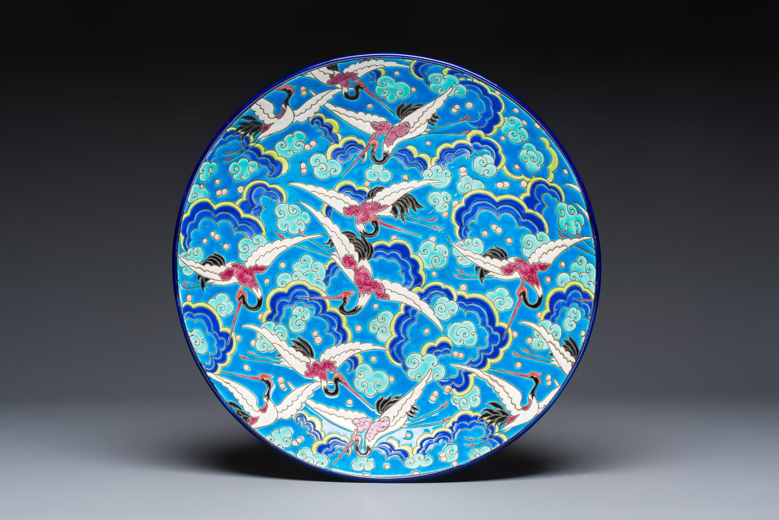 A French polychrome enamelled Longwy 'Cranes among Clouds' charger, 20th C. (1 of 2)