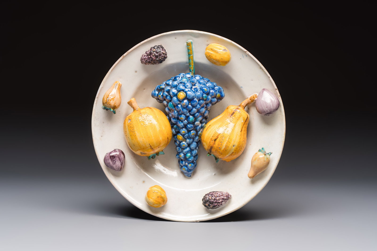 An unusual polychrome Swiss faience trompe l'oeil dish with various fruits, Winterthur, workshop of: An unusual polychrome Swiss faience trompe l'oeil dish with various fruits, Winterthur, workshop of David Pfau II, 17th C. Dia.: 22,3 cm - H.: 6,3 cm Ref.: - The Metropolitan Museum, New York,Object N