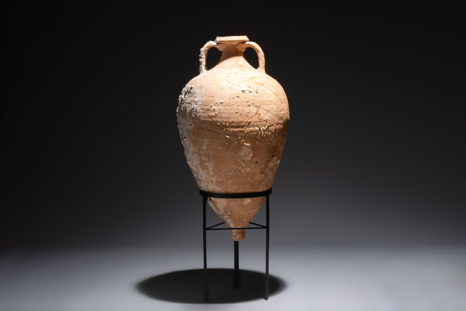 A Roman pottery olive oil transport amphora with marine encrustation, South of Spain, 1st/3rd C.: A Roman pottery olive oil transport amphora with marine encrustation, South of Spain, 1st/3rd C. H.:85 cm (incl. stand) H.:66,5 cm (excl. stand) Can be classified in the Dressel typology under number 