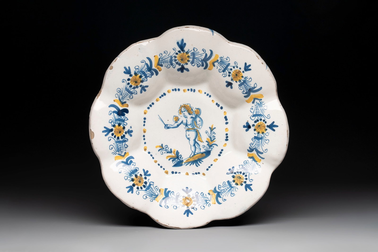 A blue, white and yellow Dutch Delftware dish with a putto, Delft or Haarlem, 17th C. (1 of 2)