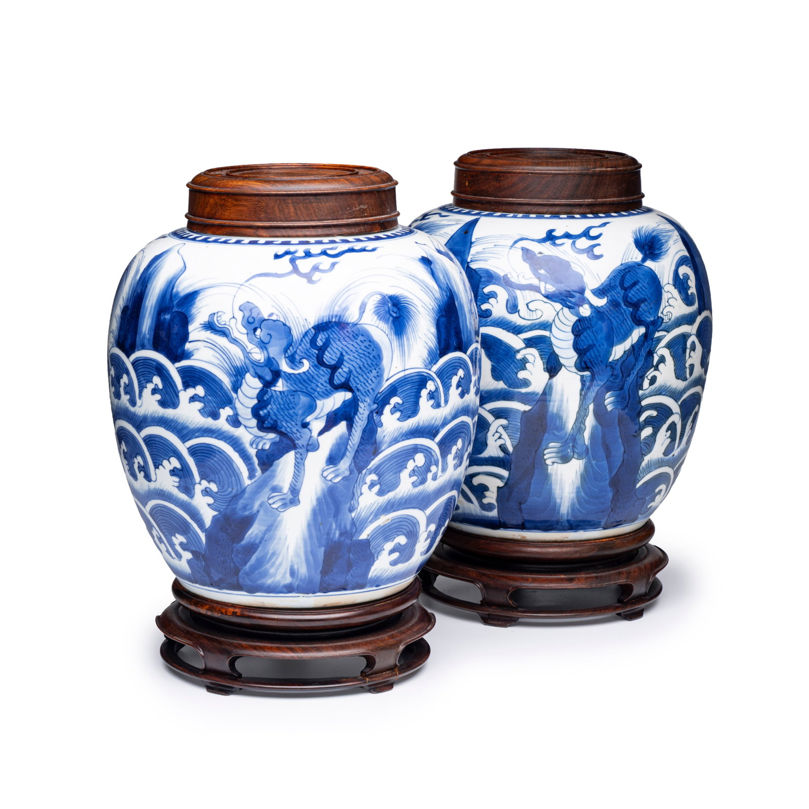 A pair of Chinese blue and white 'Mythical Beast' jars with later wooden covers and stands, Kangxi: A pair of Chinese blue and white 'Mythical Beast' jars with later wooden covers and stands, Kangxi H.: 27,5 cm | incl. cover and stand H.: 20,5 cm | excl. cover and stand Provenance: - The Mr. and Mrs
