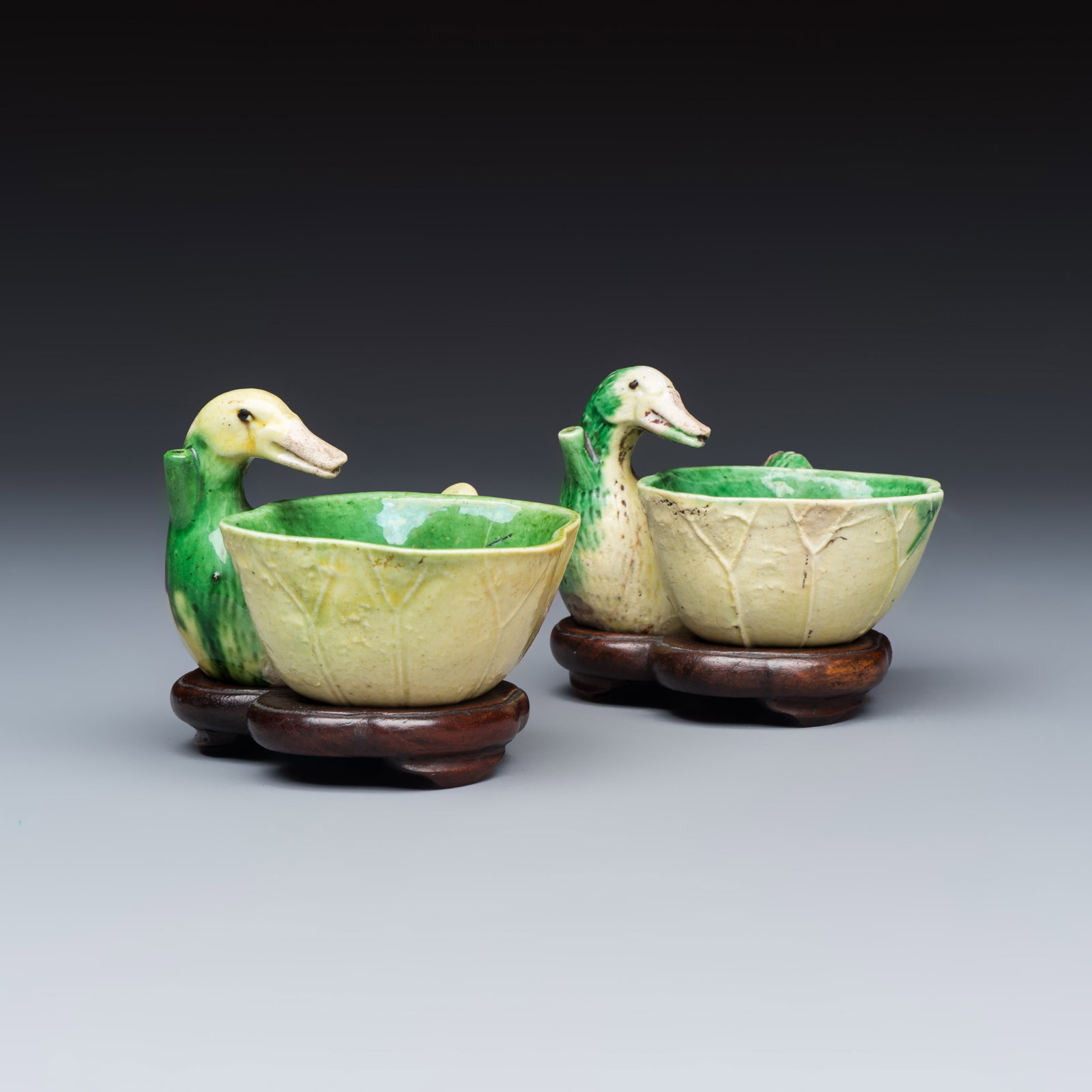 A pair of Chinese famille verte sancai biscuit duck-and-lotus-form water droppers on later wooden: A pair of Chinese famille verte sancai biscuit duck-and-lotus-form water droppers on later wooden stands, Kangxi Dim: 7 x 8,5 x 6,8 cm | incl. stand Dim: 7 x 8,5 x 5,5 cm | excl. stand