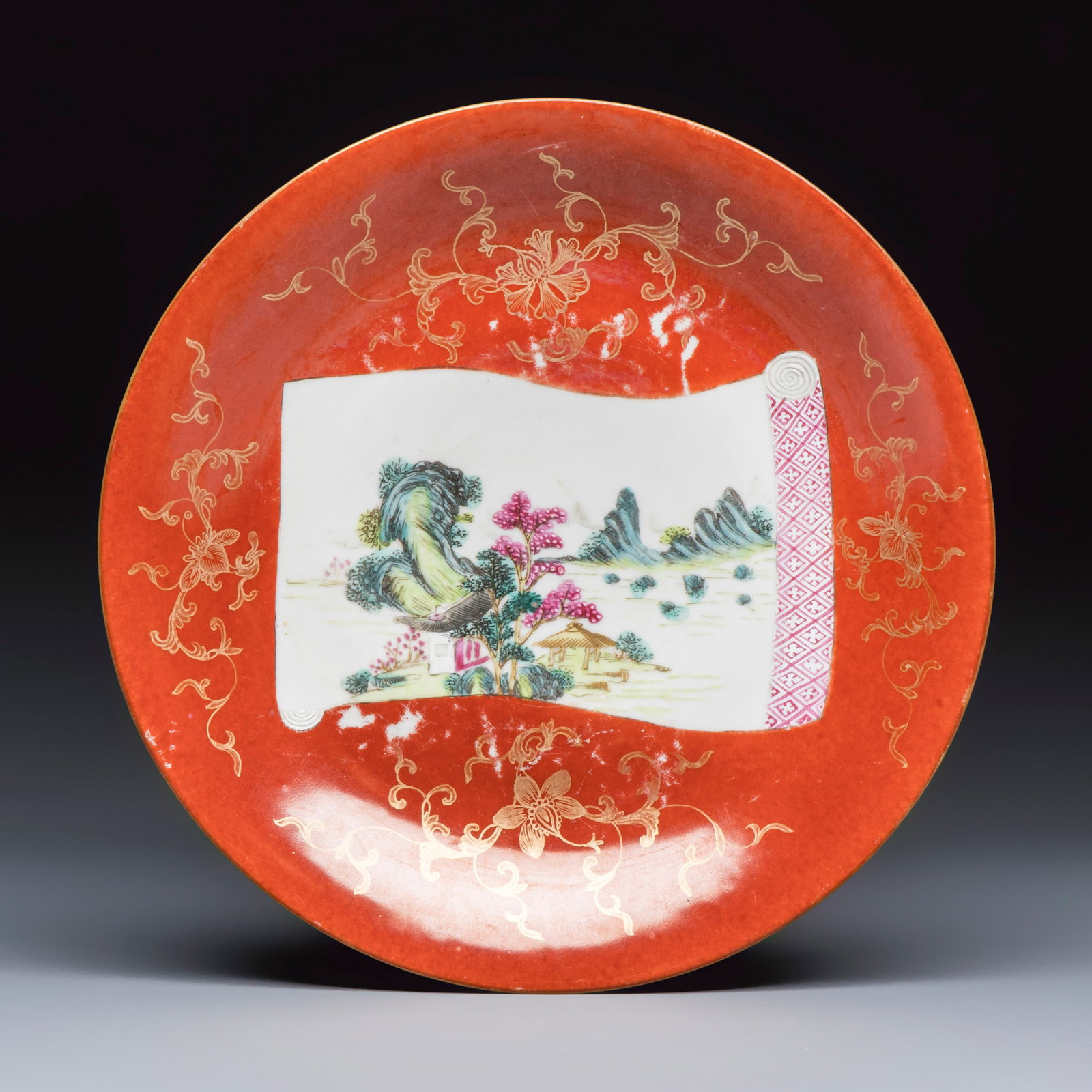 A Chinese famille rose coral-red-ground 'Landscape scroll' dish, Qianlong mark and of the period: A Chinese famille rose coral-red-ground 'Landscape scroll' dish, Qianlong mark and of the period Dia.: 26,3 cm