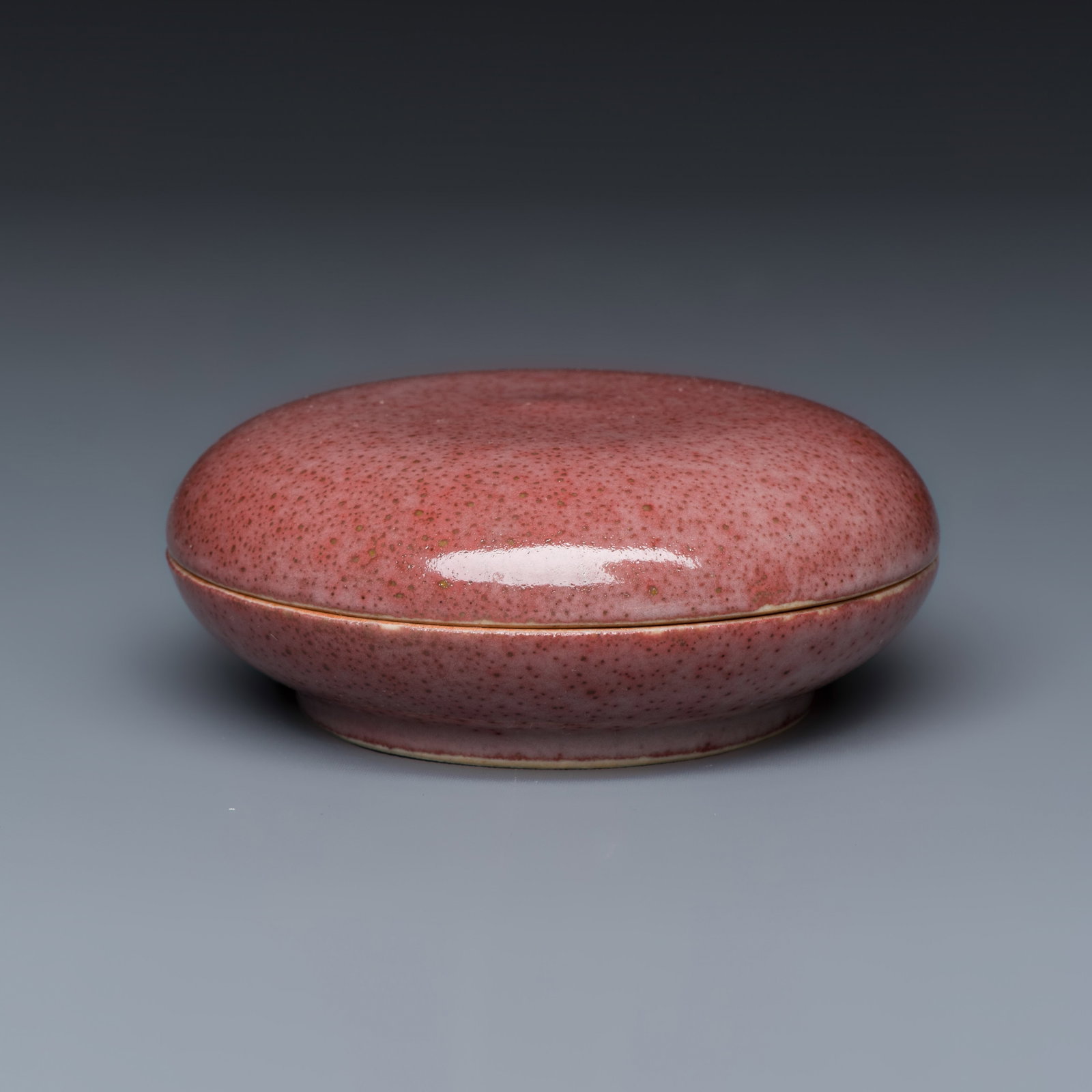 A Chinese peachbloom-glazed seal paste box, Kangxi mark, 19th C.: A Chinese peachbloom-glazed seal paste box, Kangxi mark, 19th C. Dia.: 8,8 cm - H.: 3,6 cm | incl. cover