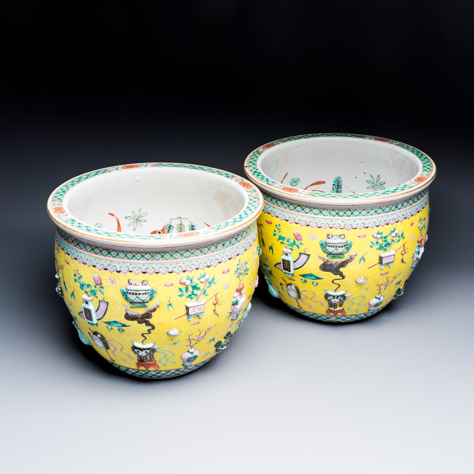 A pair of Chinese famille rose yellow-ground 'Antiquities' fish bowls with applied relief design, (1 of 7)