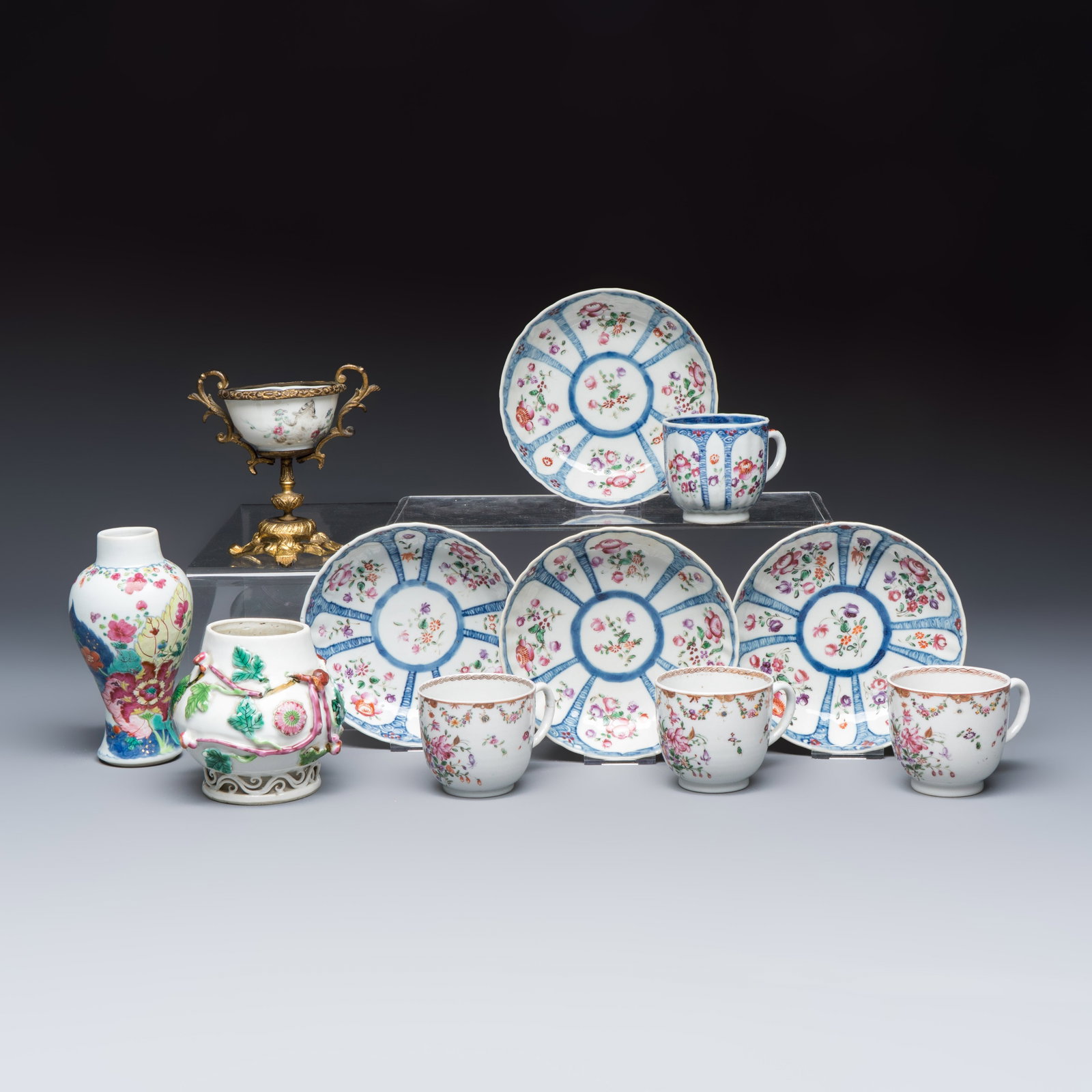 11 Chinese famille rose wares, one with gilt-bronze mounts, Yongzheng/Qianlong: 11 Chinese famille rose wares, one with gilt-bronze mounts, Yongzheng/Qianlong Dia.: 13,6 cm | the saucers L.: 9 cm - H.: 5,9 cm | the largest cup H.: 13,6 cm | the tallest vase