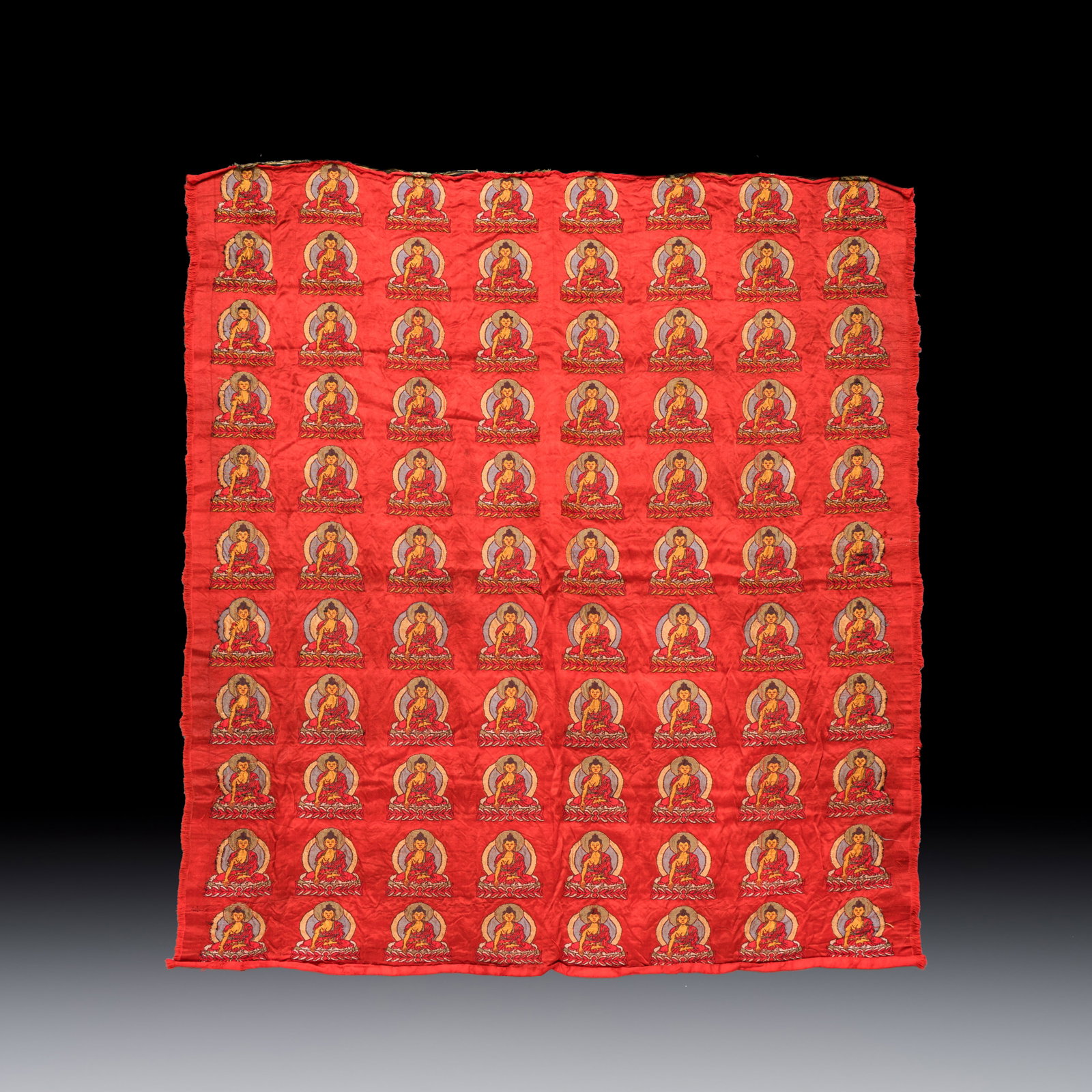 A Chinese red-ground brocade panel with seated Buddhas, 20th C. (1 of 2)